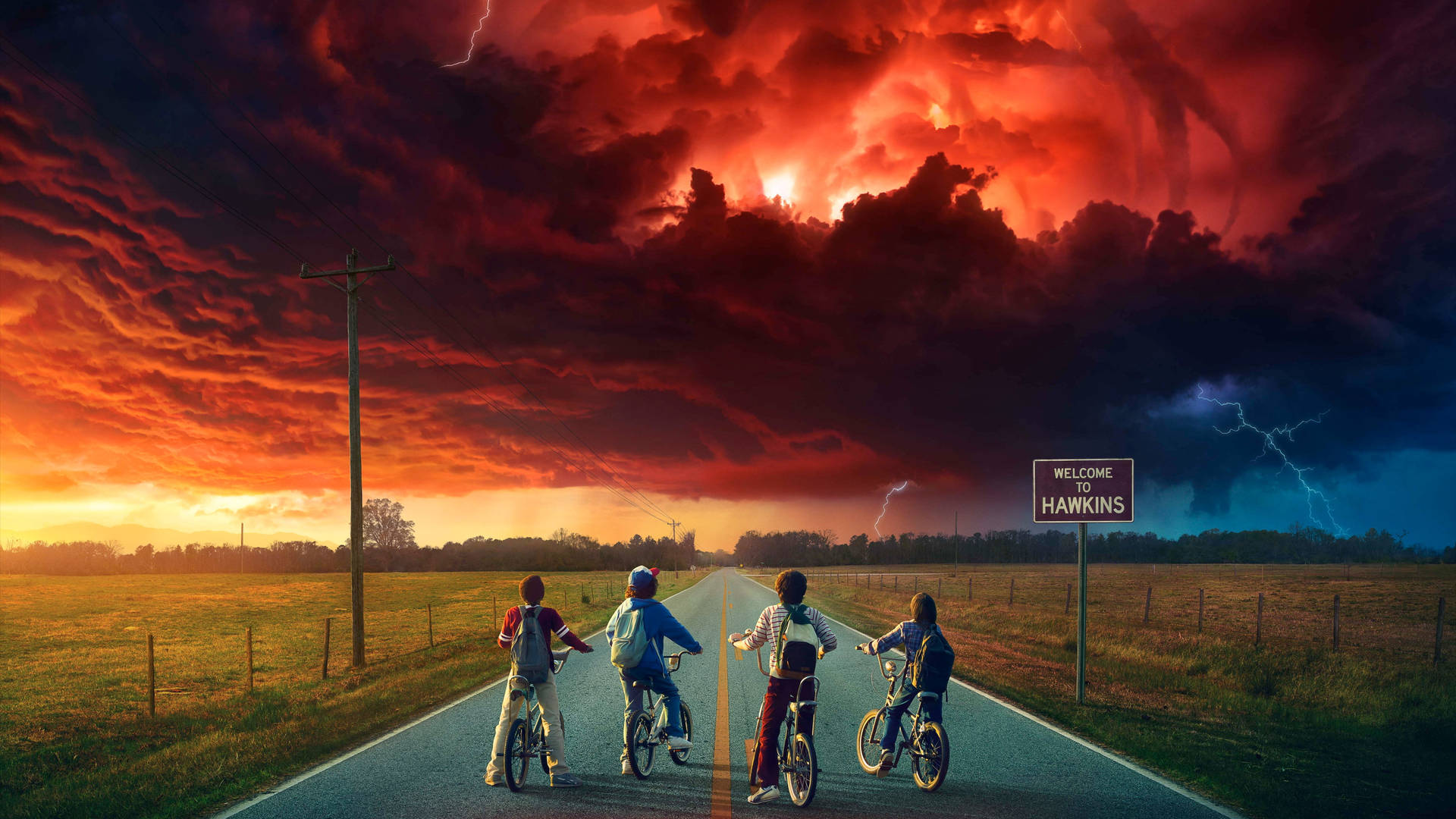 Four children on bicycles face a dramatic, stormy sky over a rural road leading to Hawkins, Indiana, in a promotional image for Stranger Things