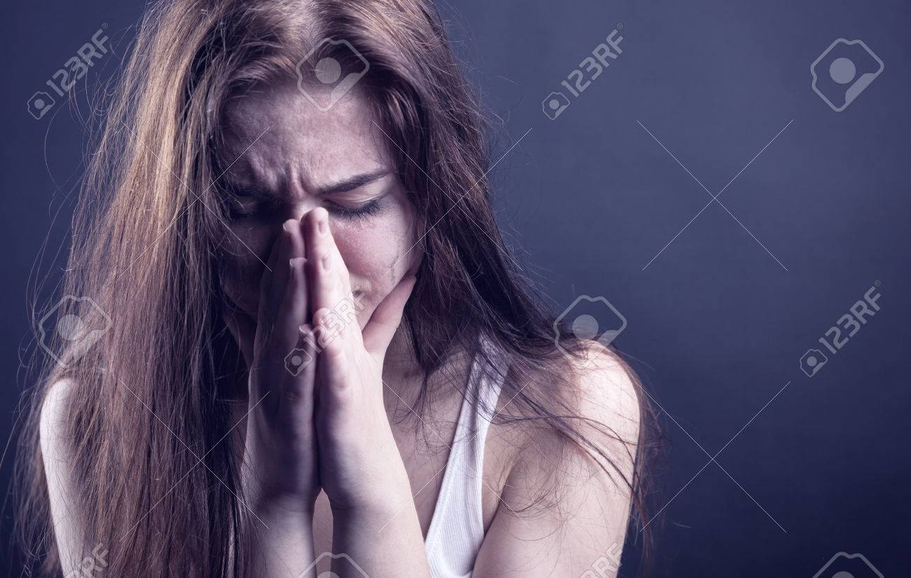 Young Woman Crying Face In Her Hands On A Dark Background Stock