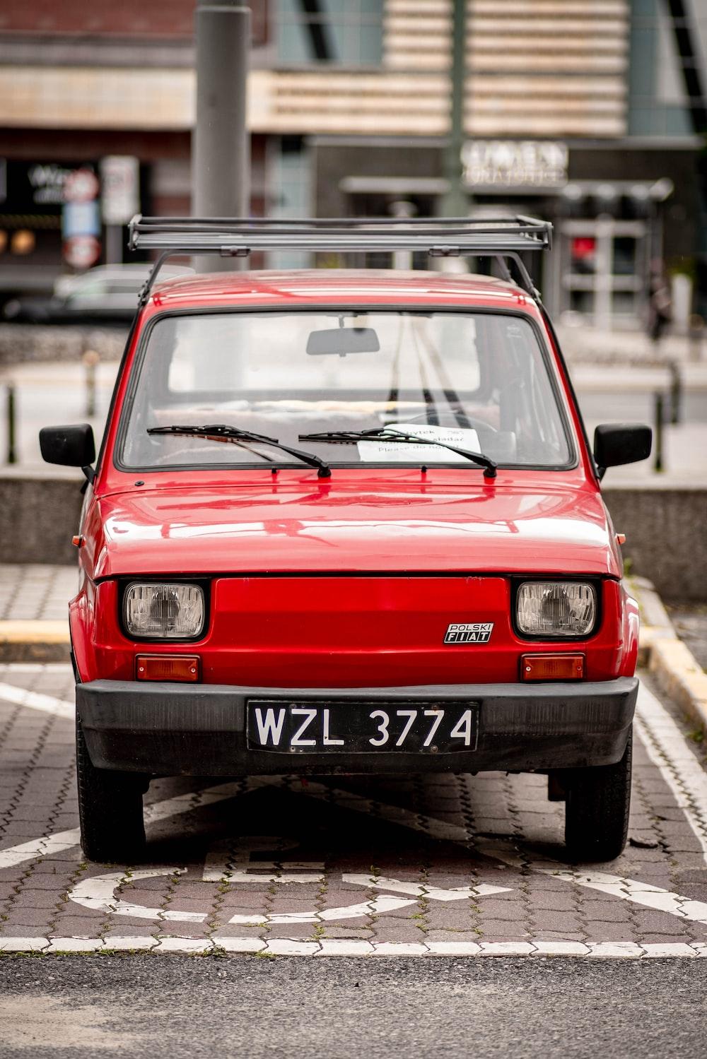Red Car Parked In Front Of Building During Daytime Photo