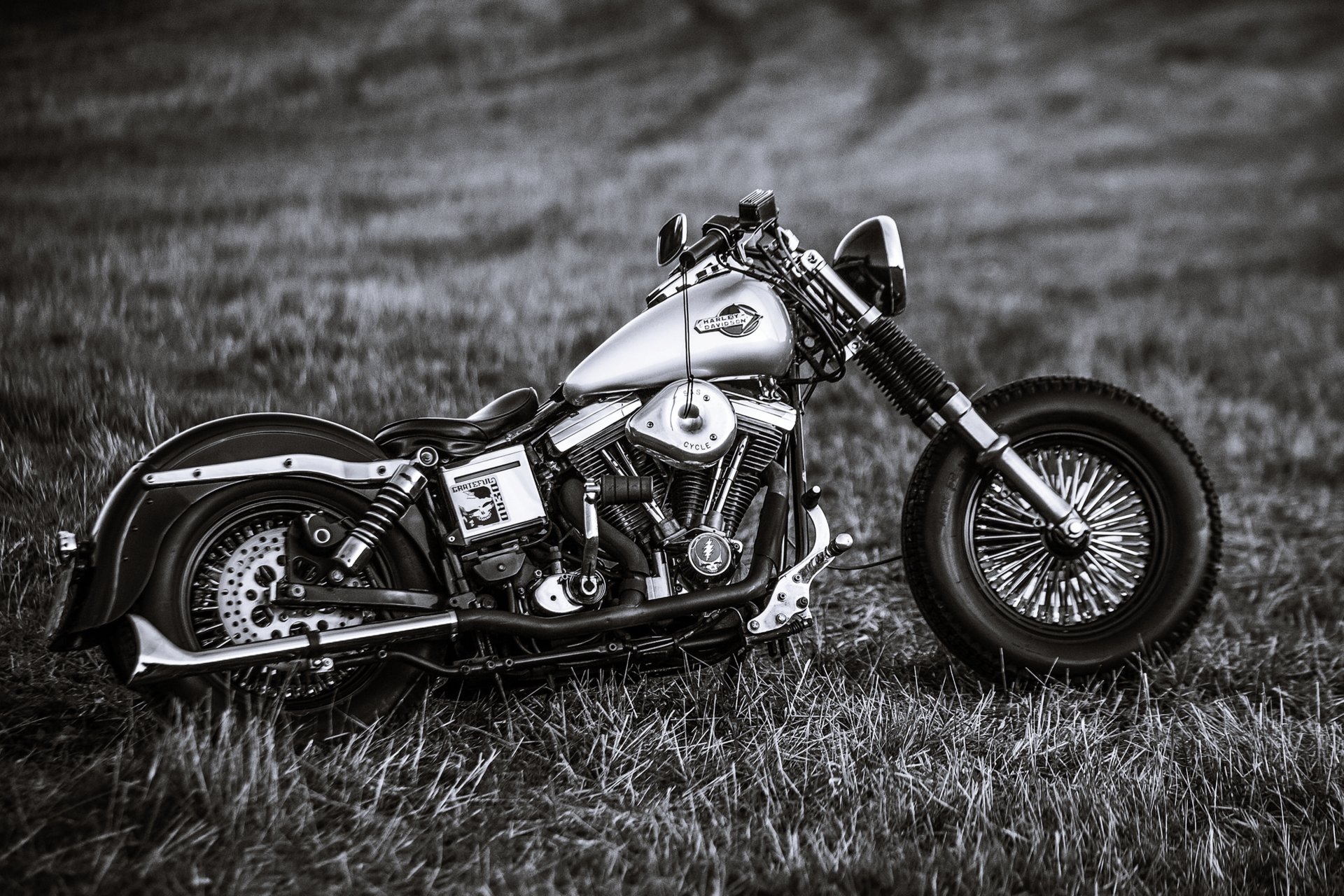Black and white photo of a vintage Harley Davidson motorcycle parked in a field