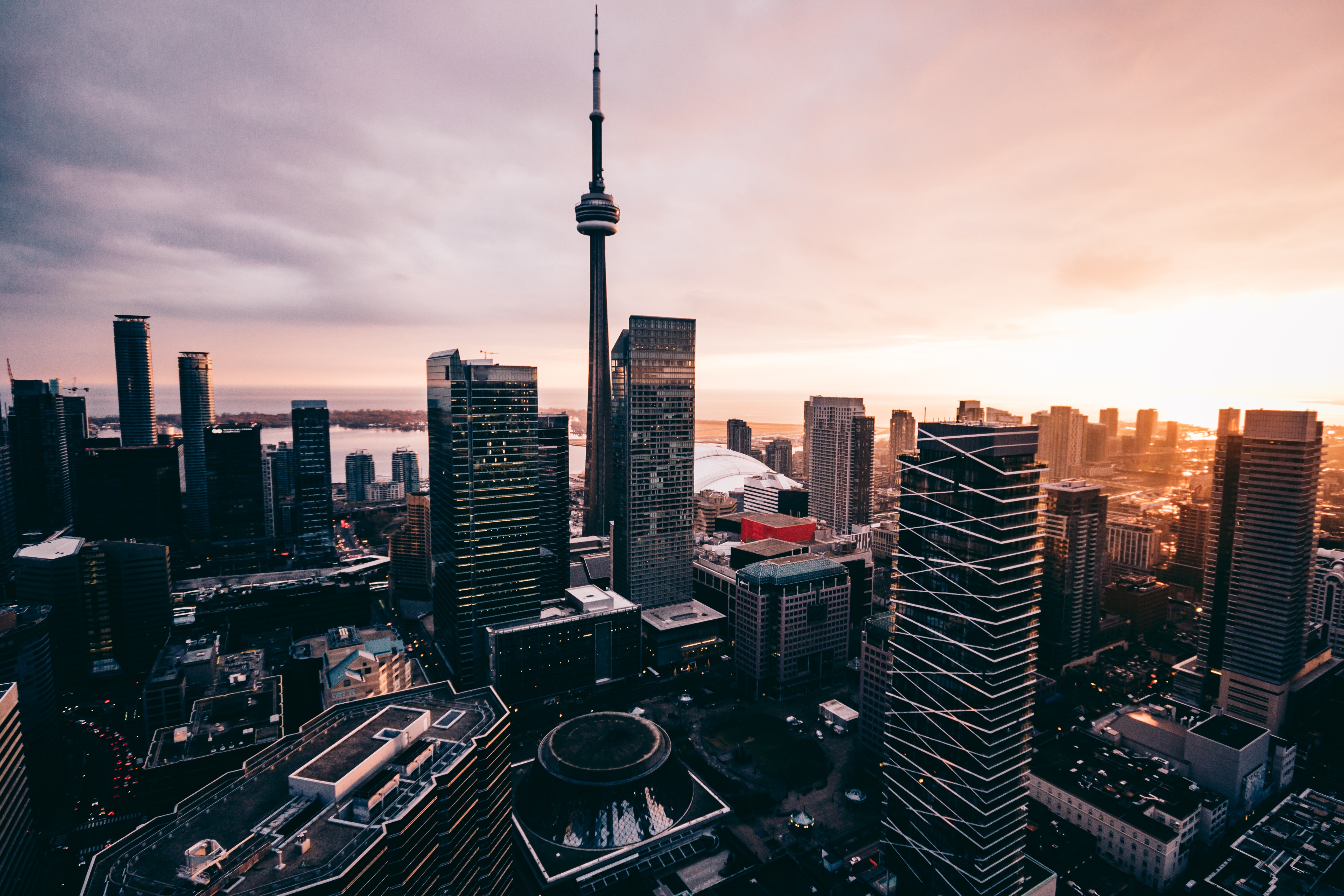 A stunning aerial view of the Toronto skyline at sunset, featuring the iconic CN Tower and modern skyscrapers
