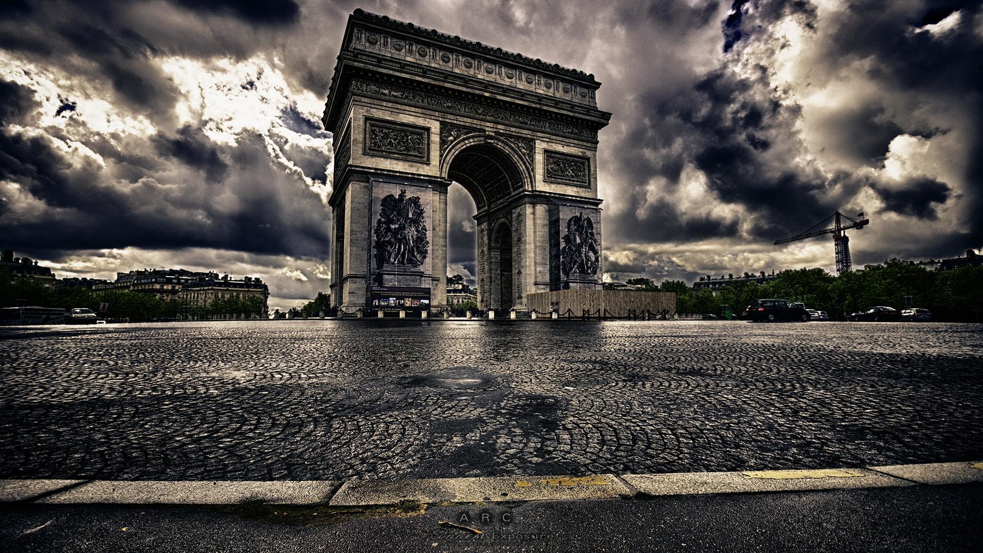 A dramatic view of the Arc de Triomphe in Paris, France, under a stormy sky