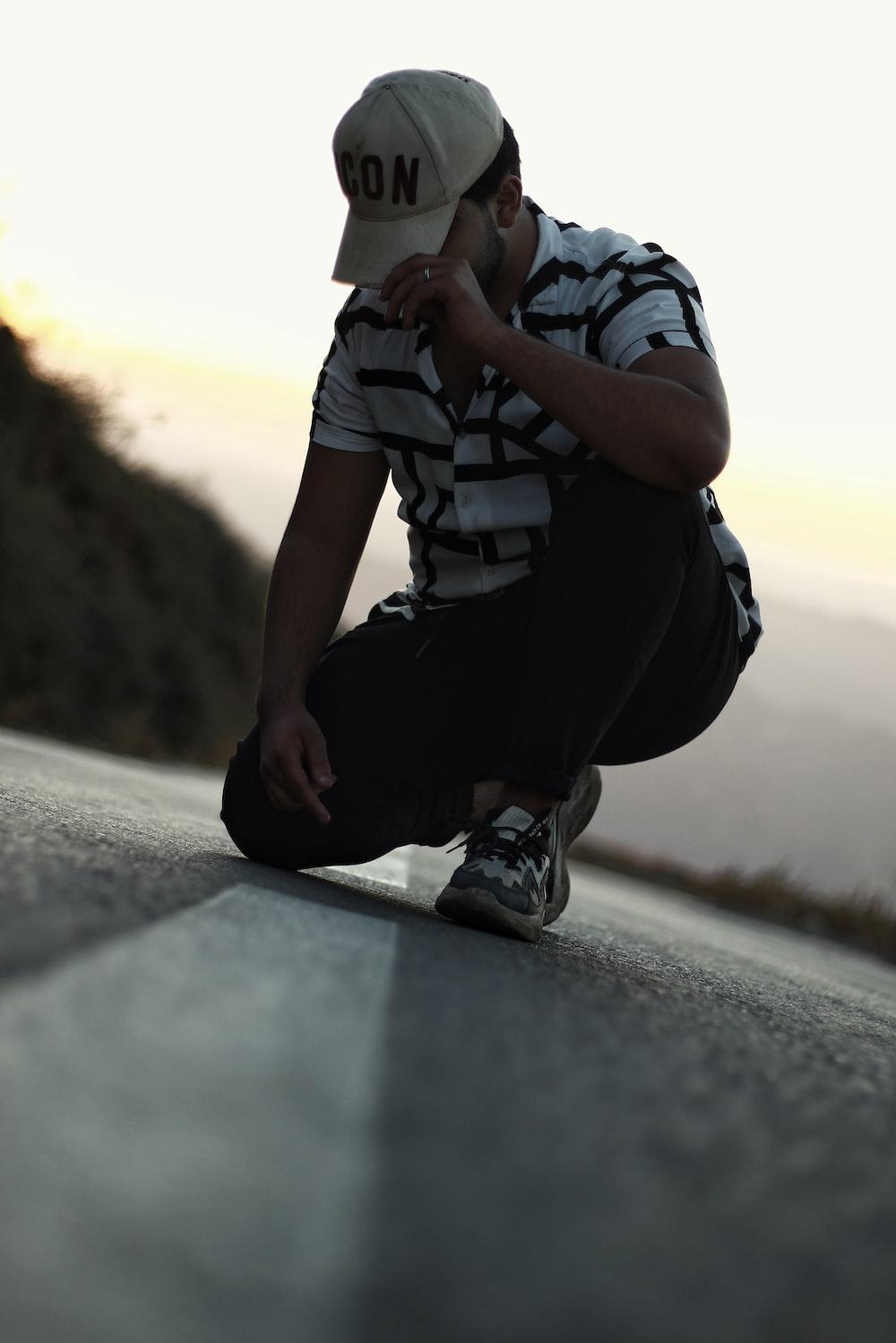 A Man Sitting On The Side Of Road Wearing Hat Photo