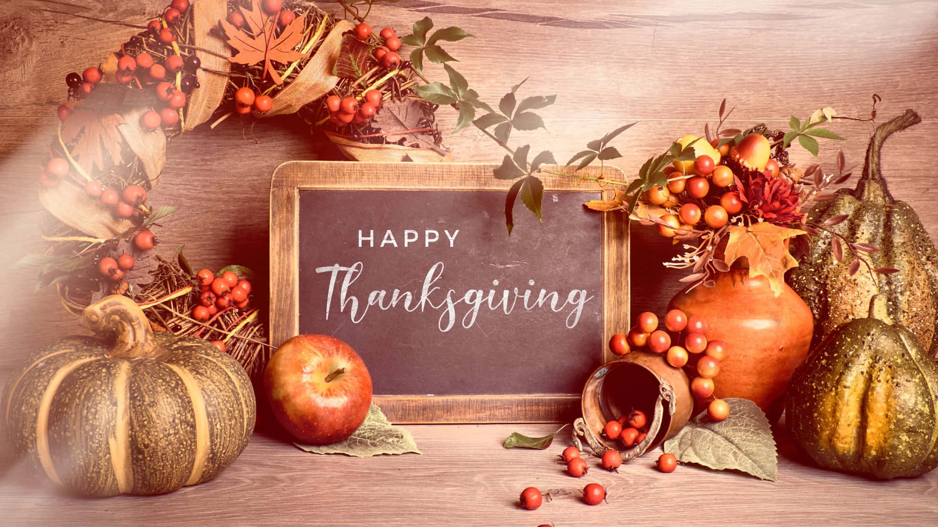 A rustic Thanksgiving still life with pumpkins, gourds, apples, berries, autumn leaves, and a chalkboard sign saying 'Happy Thanksgiving'