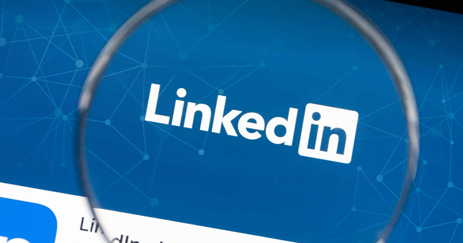 Close-up of the LinkedIn logo on a screen, viewed through a magnifying glass. This emphasizes the platform's importance for professional networking and job searching