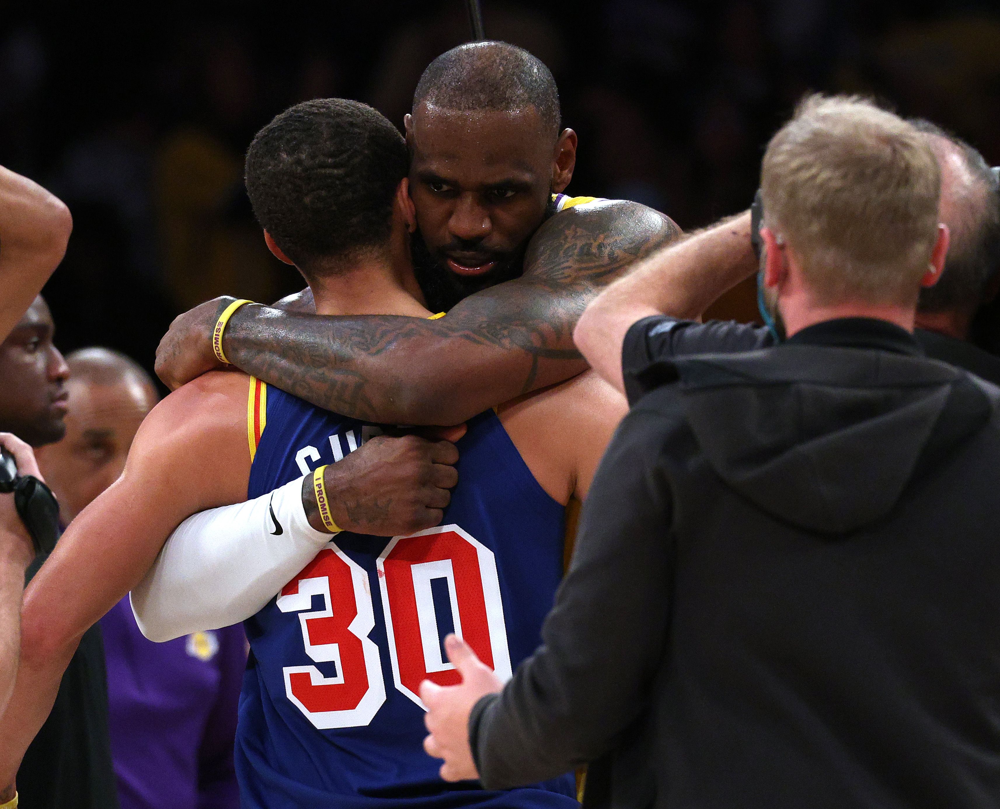 LeBron James and Stephen Curry embrace after a game, showcasing their respect and sportsmanship
