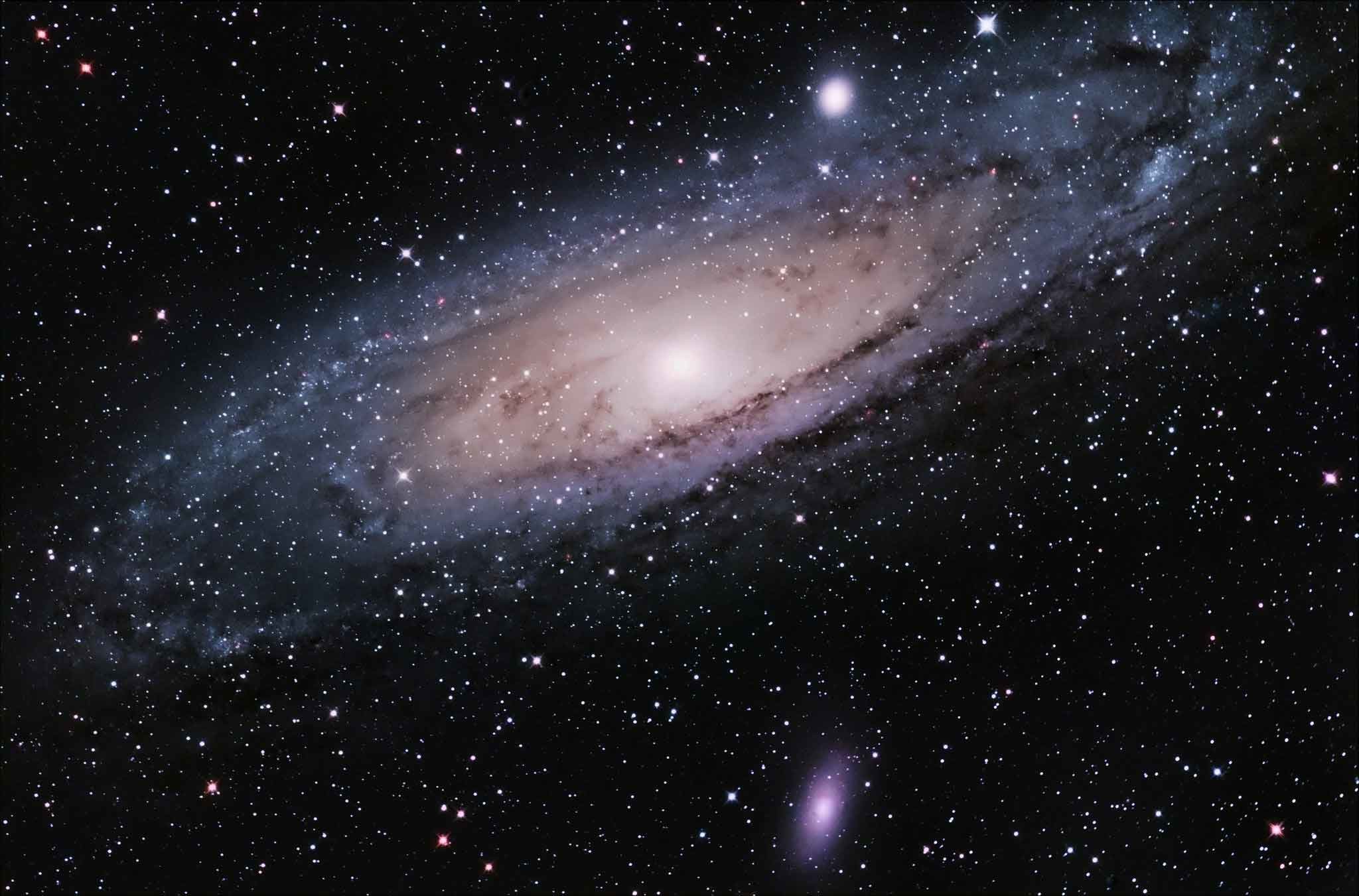 A stunning spiral galaxy, viewed at a slight angle, dominates the frame against the backdrop of a dark, star-studded sky