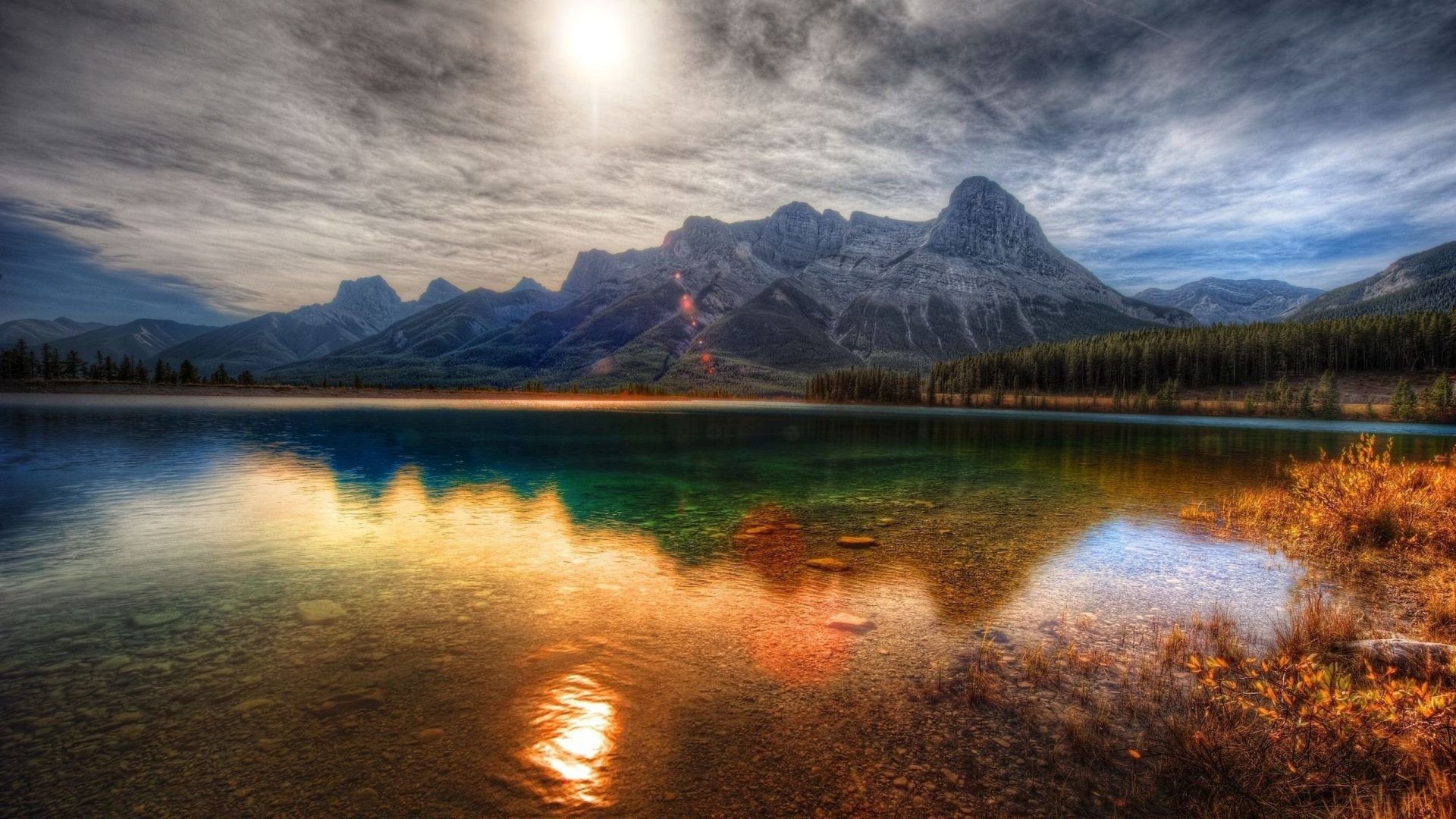 Stunning HD wallpaper of a pristine mountain lake reflecting the sun and majestic peaks, perfect for phone backgrounds