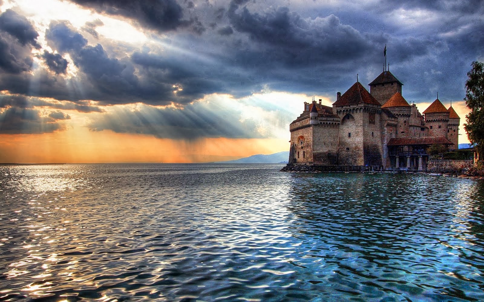 Majestic castle on a lake at sunset with dramatic clouds and sun rays