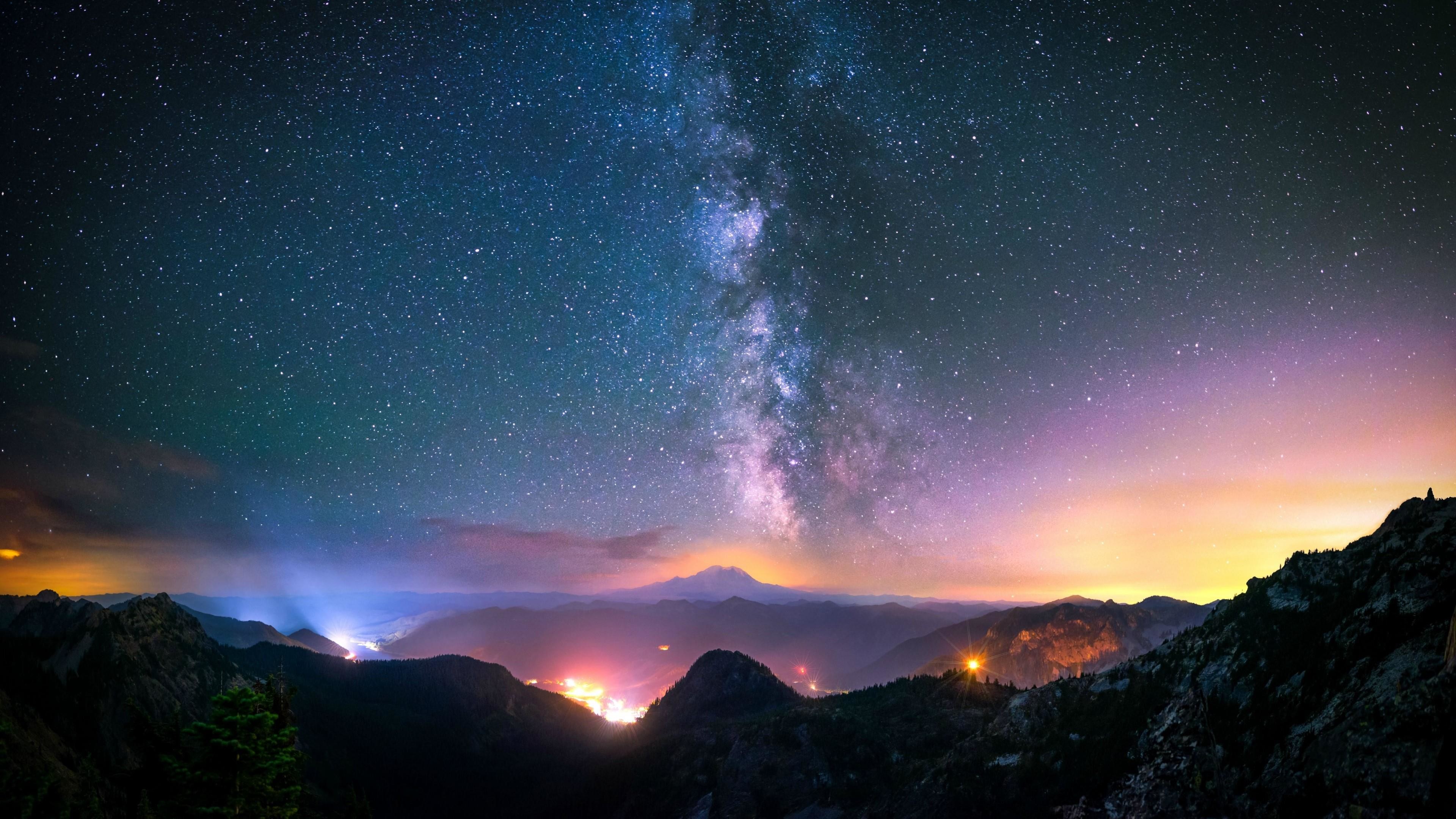 A breathtaking panorama of a starry night sky with the Milky Way prominently displayed, illuminating the silhouette of a mountain range below