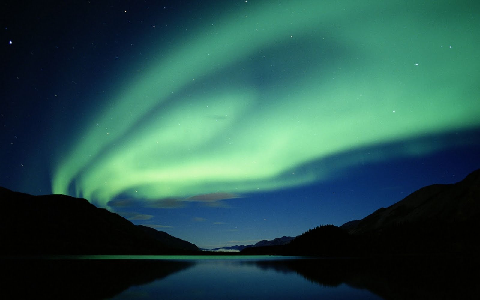 A breathtaking aurora borealis display illuminates the night sky over a serene lake, creating a stunning natural light show