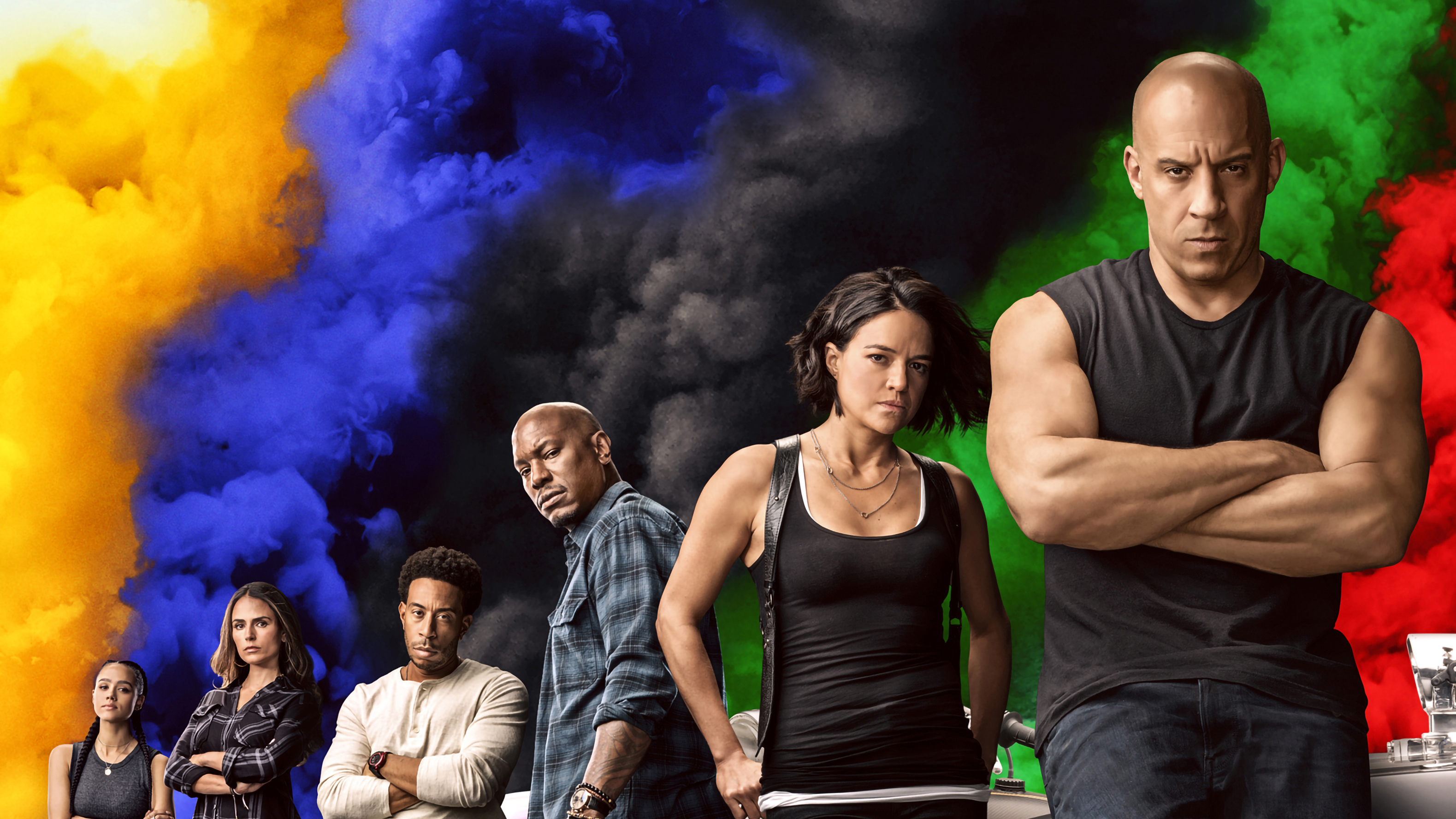 The main cast of Fast X, the tenth film in the Fast and Furious franchise, standing against a backdrop of colorful smoke