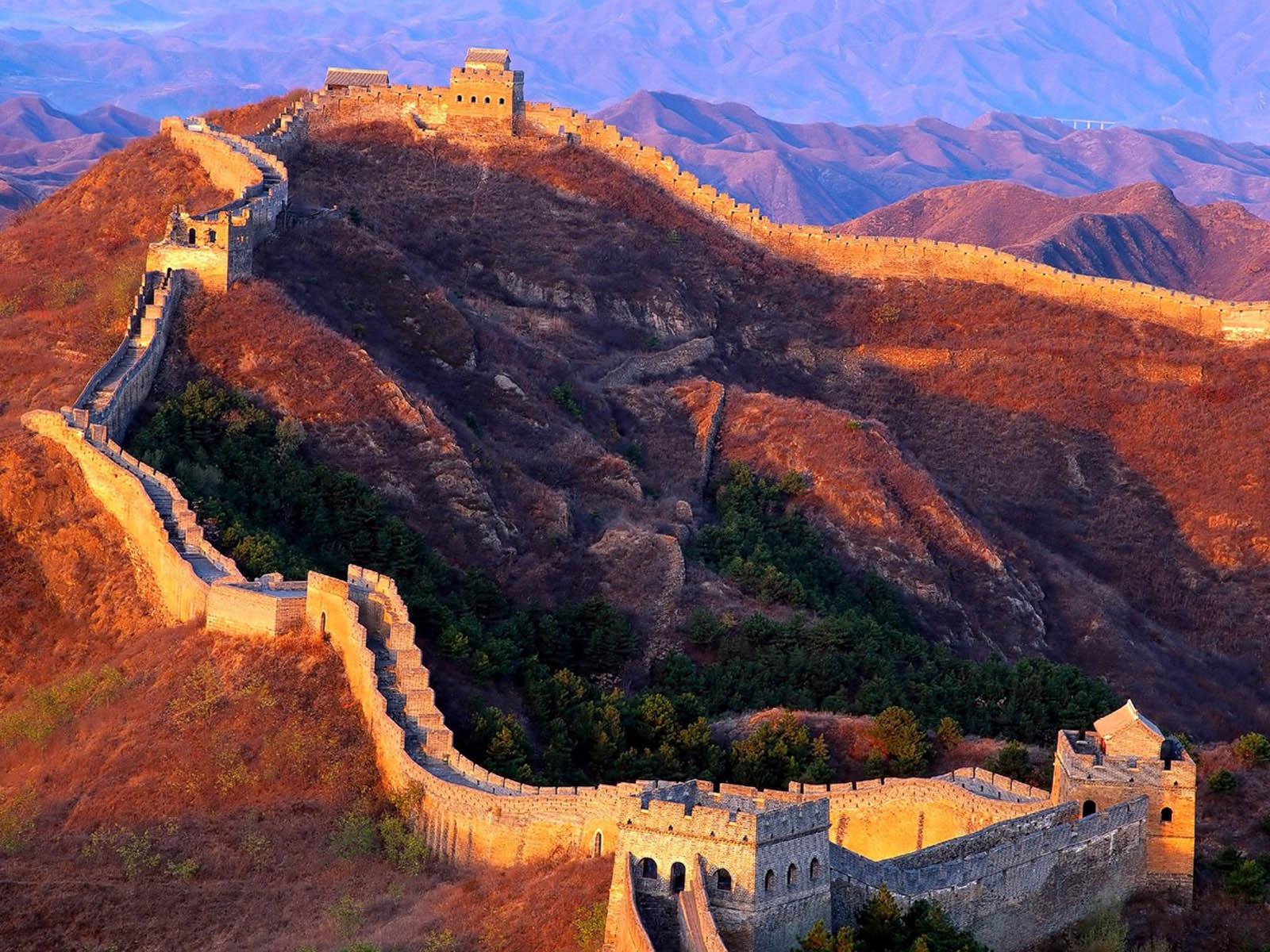 The Great Wall of China winds through the mountains at sunset, showcasing its ancient strength and beauty