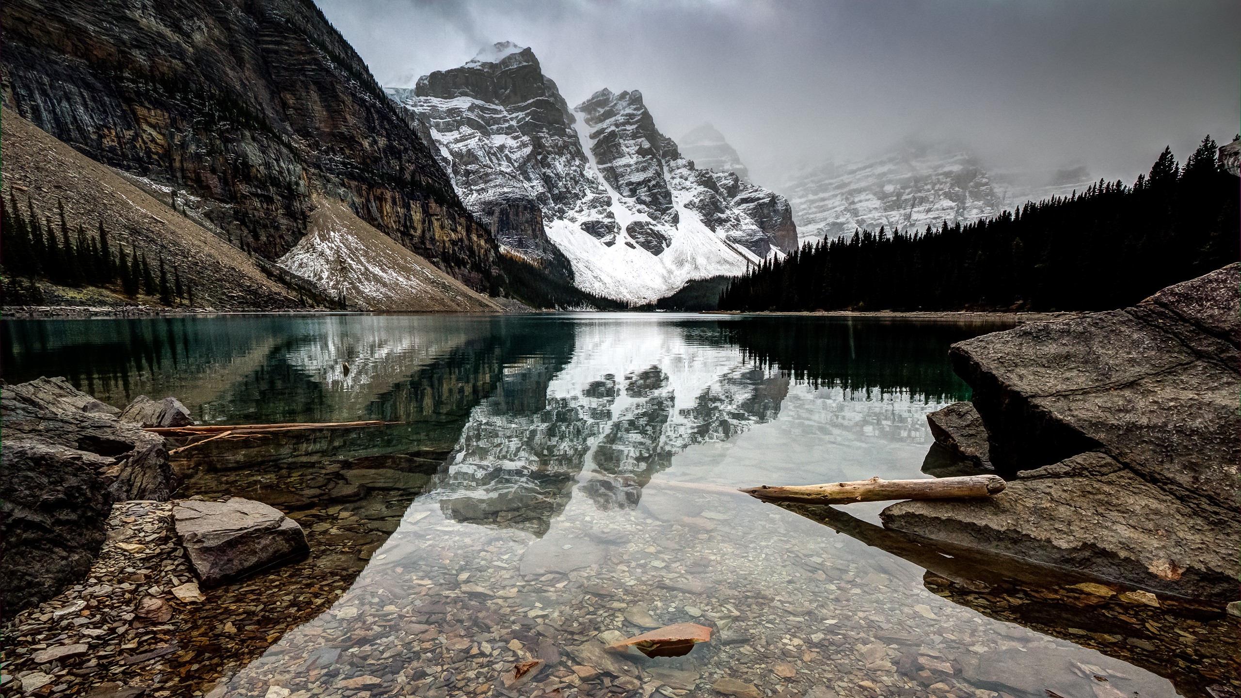 A breathtaking view of Moraine Lake in Banff National Park, with crystal-clear turquoise water reflecting the surrounding snow-capped mountains and lush forest