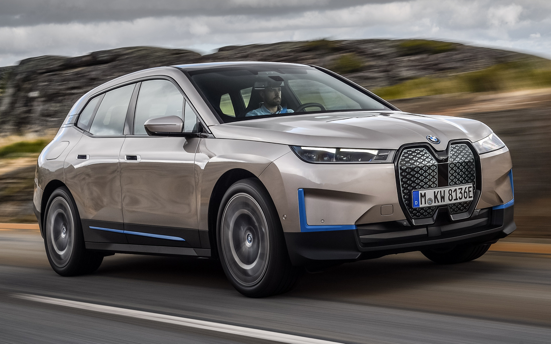 A BMW iX electric SUV driving on a scenic highway