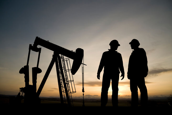 Oil Well And Two Workers At Dusk