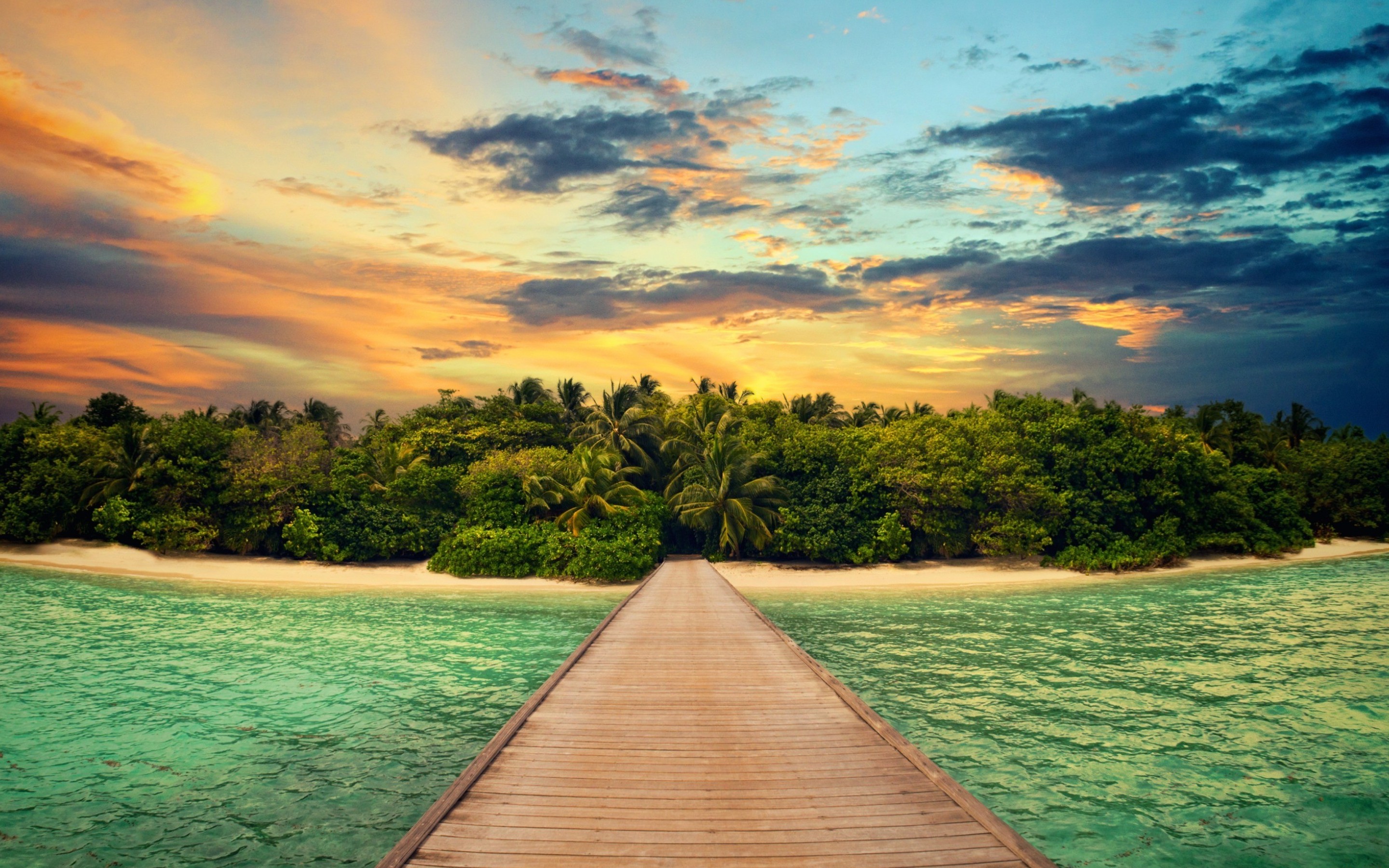 A wooden pier leading to a tropical island paradise at sunset. Lush vegetation, white sand beach, and calm turquoise water