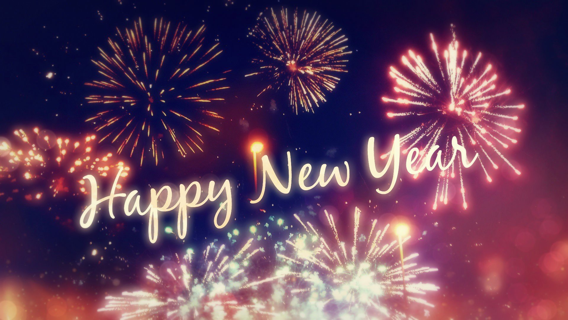 Fireworks exploding in the night sky with the text 'Happy New Year' overlaid on top