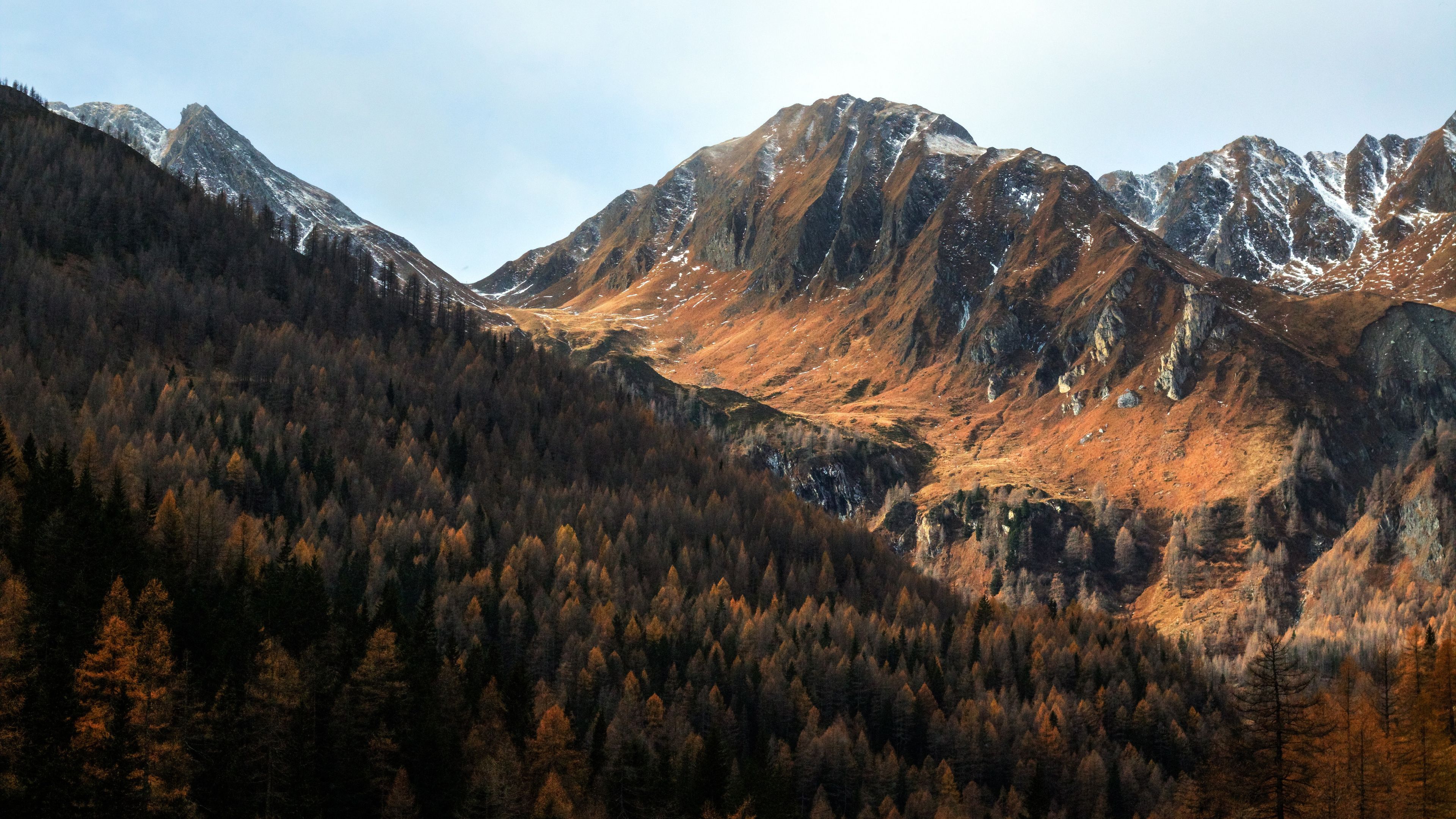 Scenic 4k wallpaper of a mountain range with autumn foliage and a dusting of snow