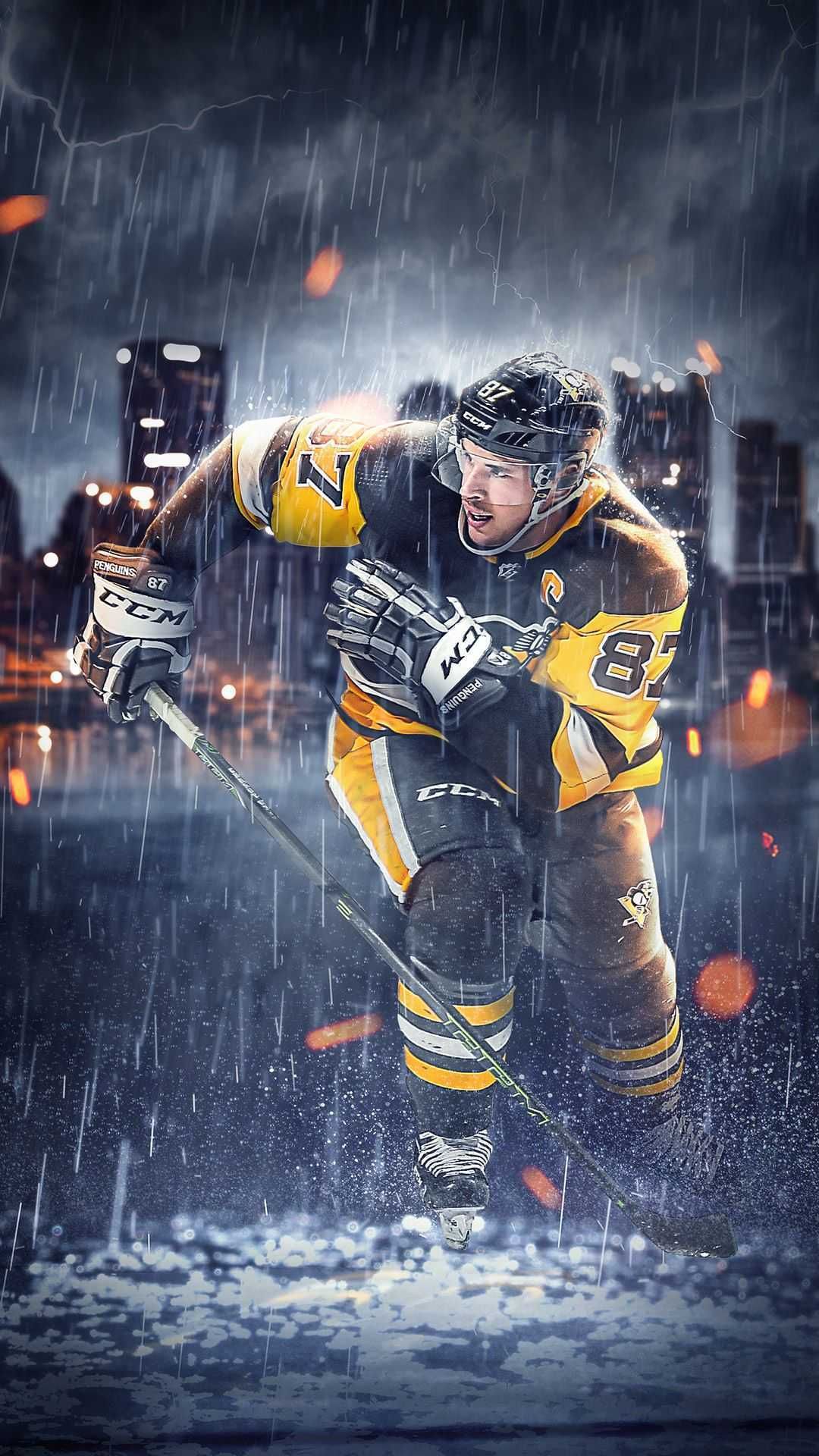 A hockey player skates through the rain on an outdoor rink, wearing a yellow and black uniform