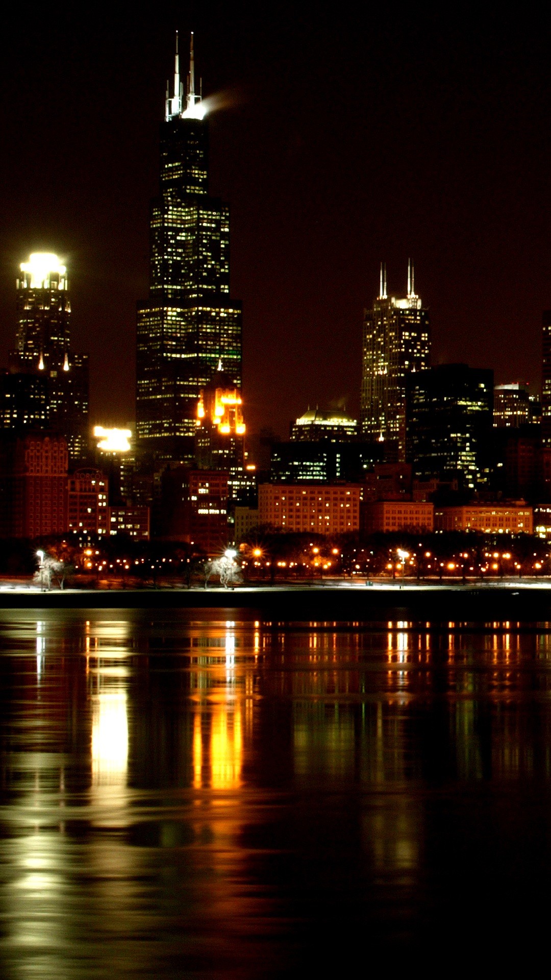 Chicago skyline at night with the John Hancock Center prominently displayed and its reflection in the water of Lake Michigan