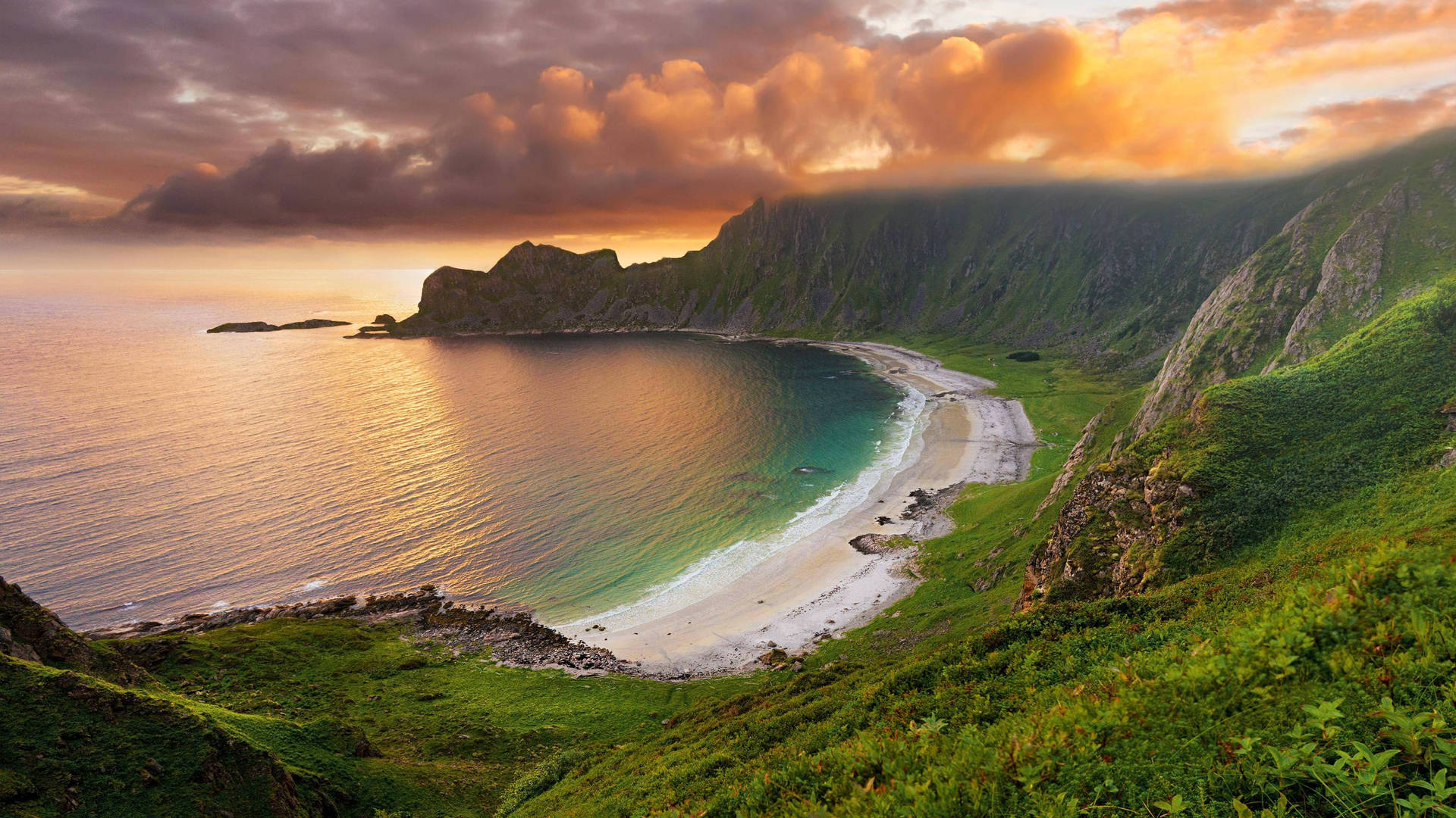 A breathtaking aerial view of a secluded beach nestled between dramatic cliffs at sunset