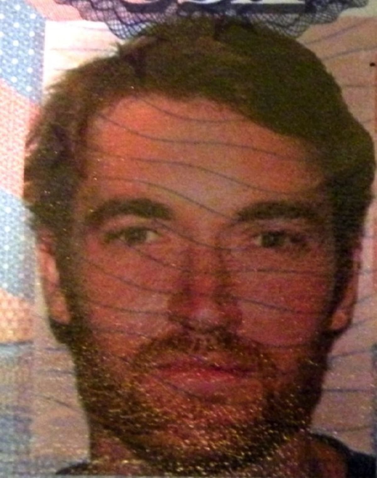 A man's face, partially obscured by a mesh-like overlay