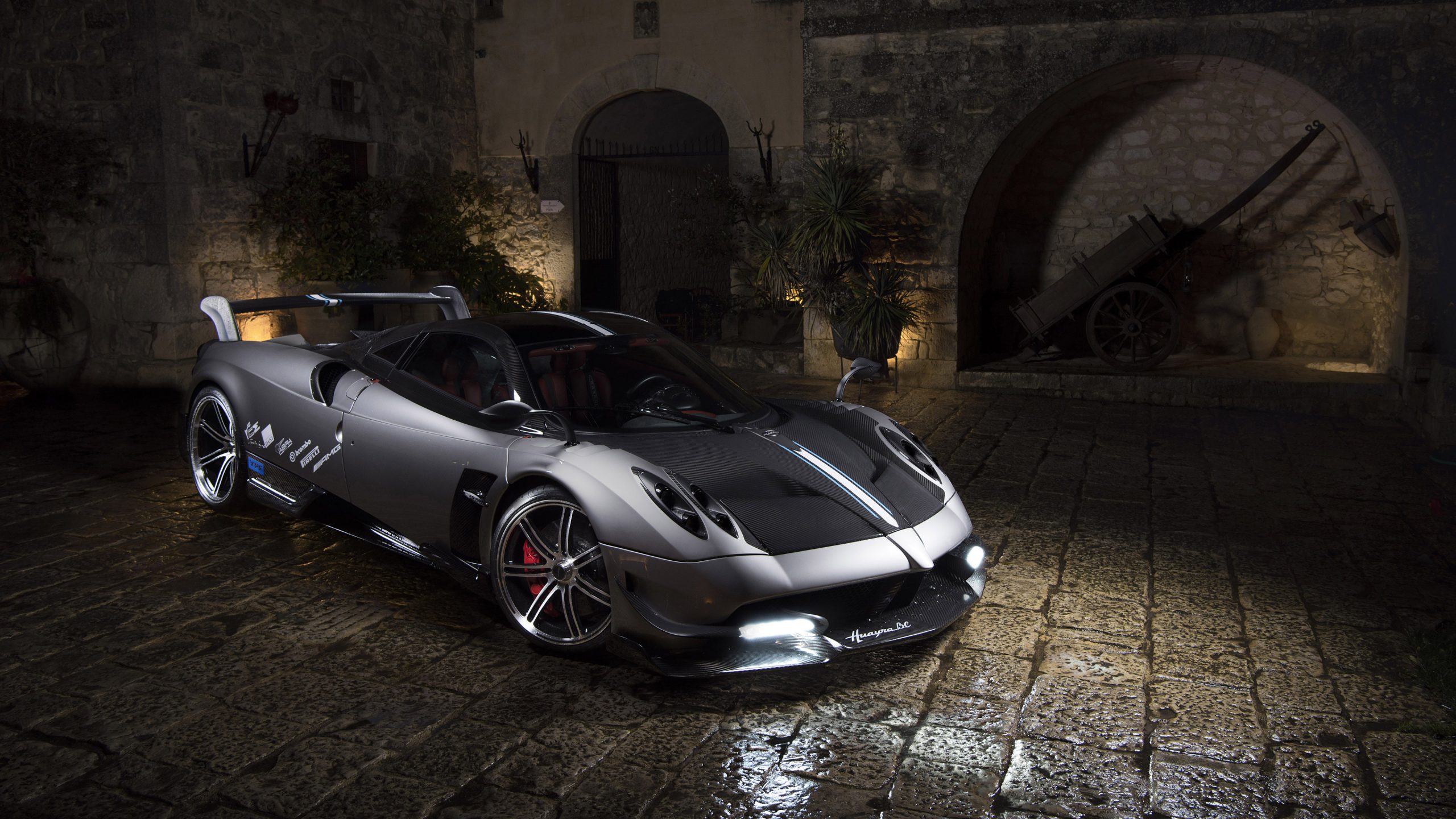 A sleek silver Pagani Huayra supercar parked on a cobblestone street at night