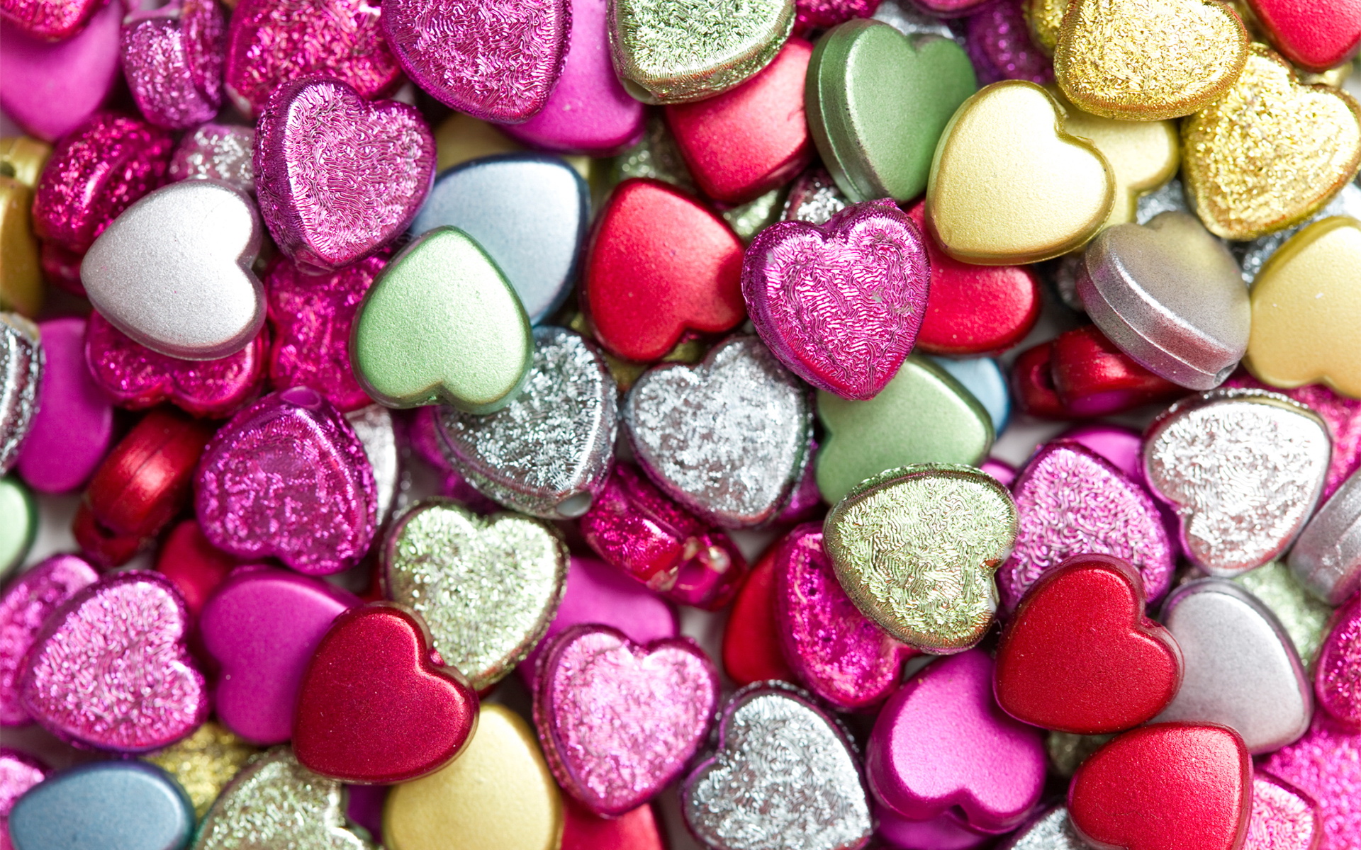 A close-up view of a pile of colorful heart-shaped beads, creating a vibrant and romantic background