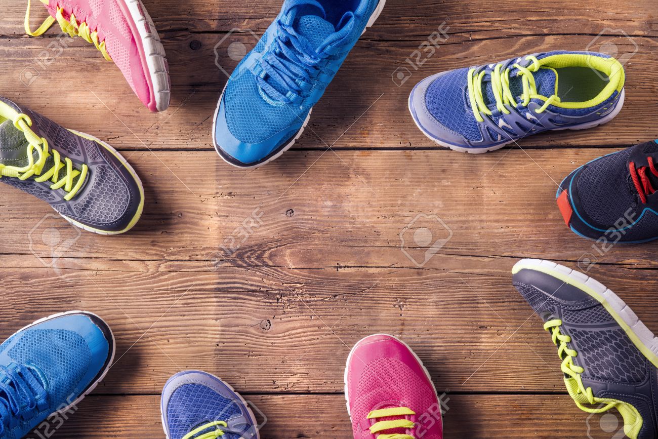 Various Running Shoes Laid On A Wooden Floor Background Stock