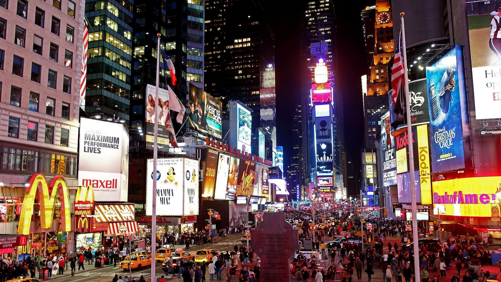 A vibrant night view of New York City's Times Square, showcasing the dazzling lights of Broadway shows and bustling crowds