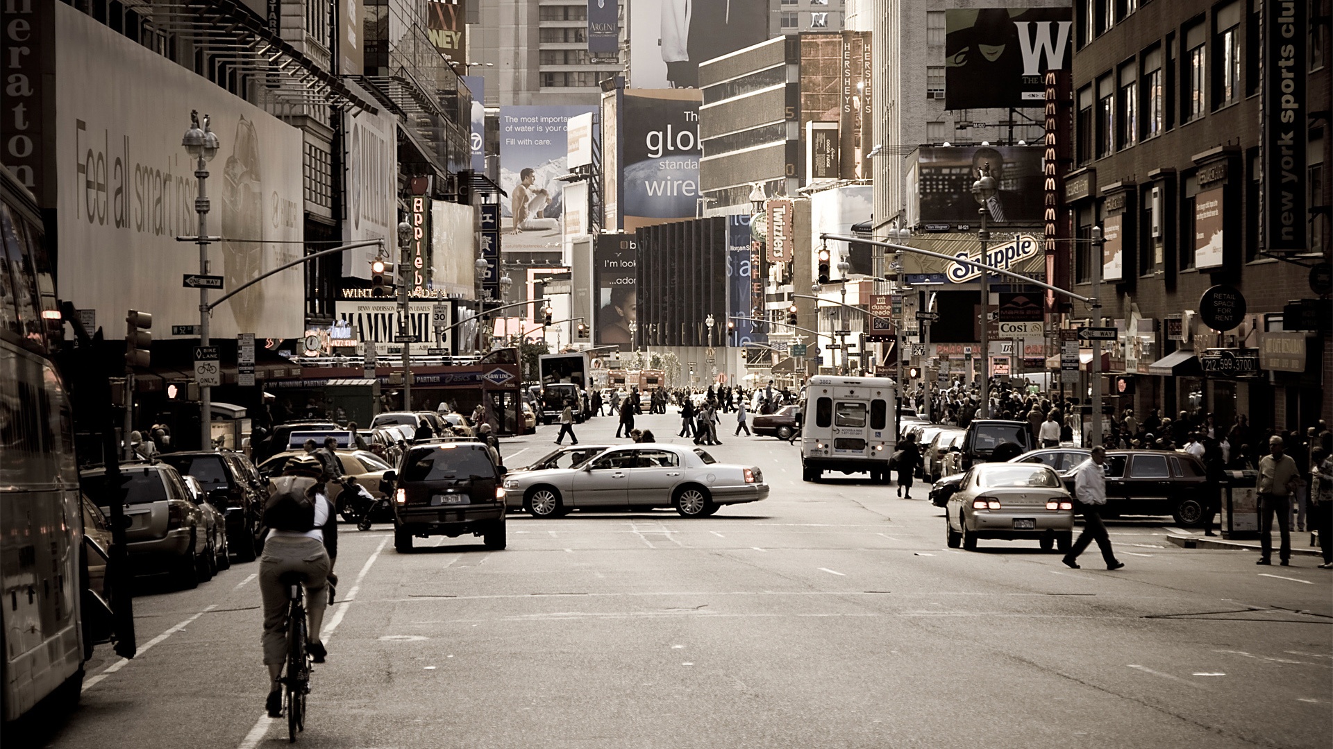 A vintage sepia-toned photograph of Broadway in New York City, showcasing the bustling street filled with traffic, pedestrians, and iconic billboards