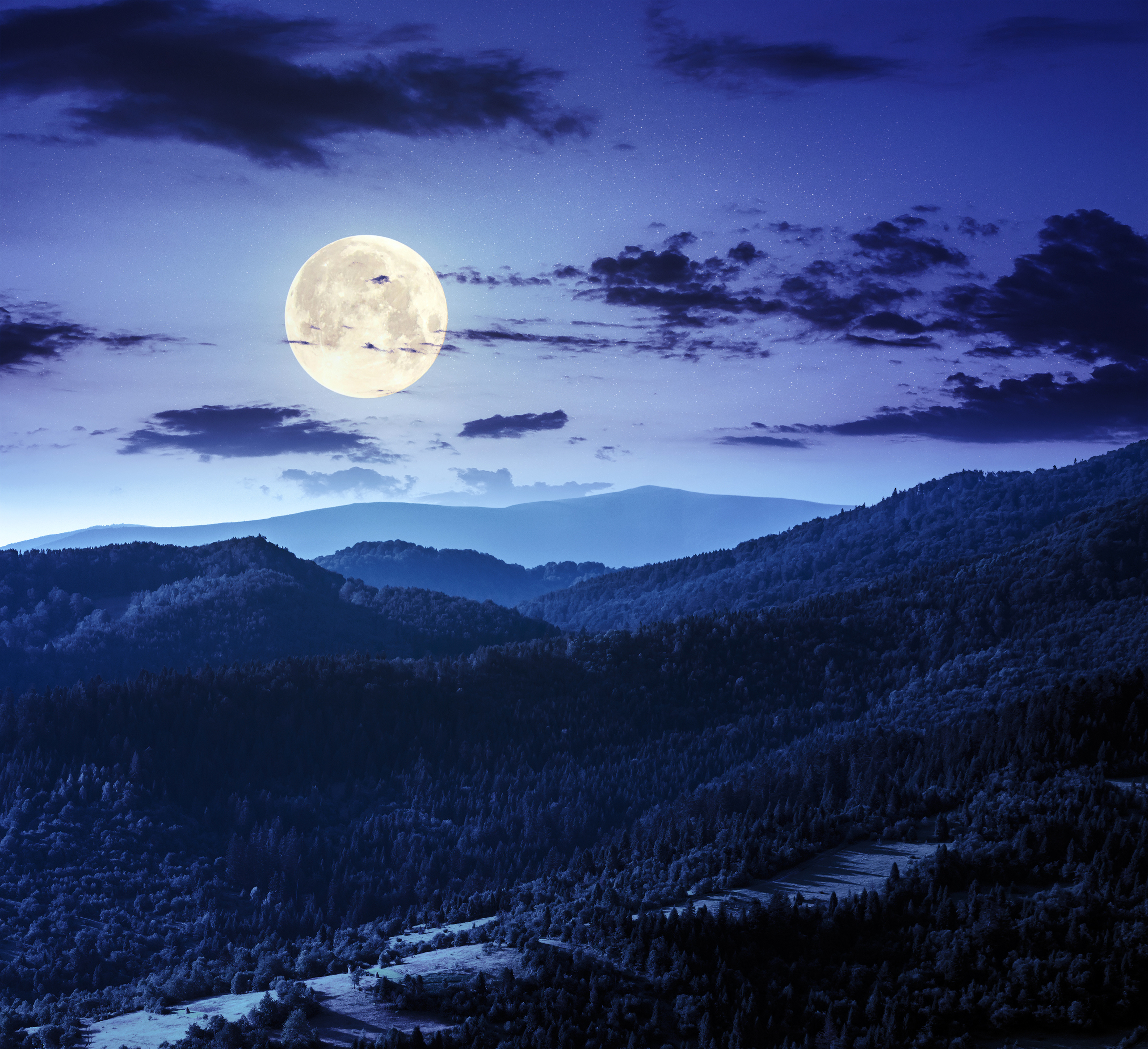 Stunning 4k wallpaper of a night sky with a bright full moon illuminating a forested mountain range