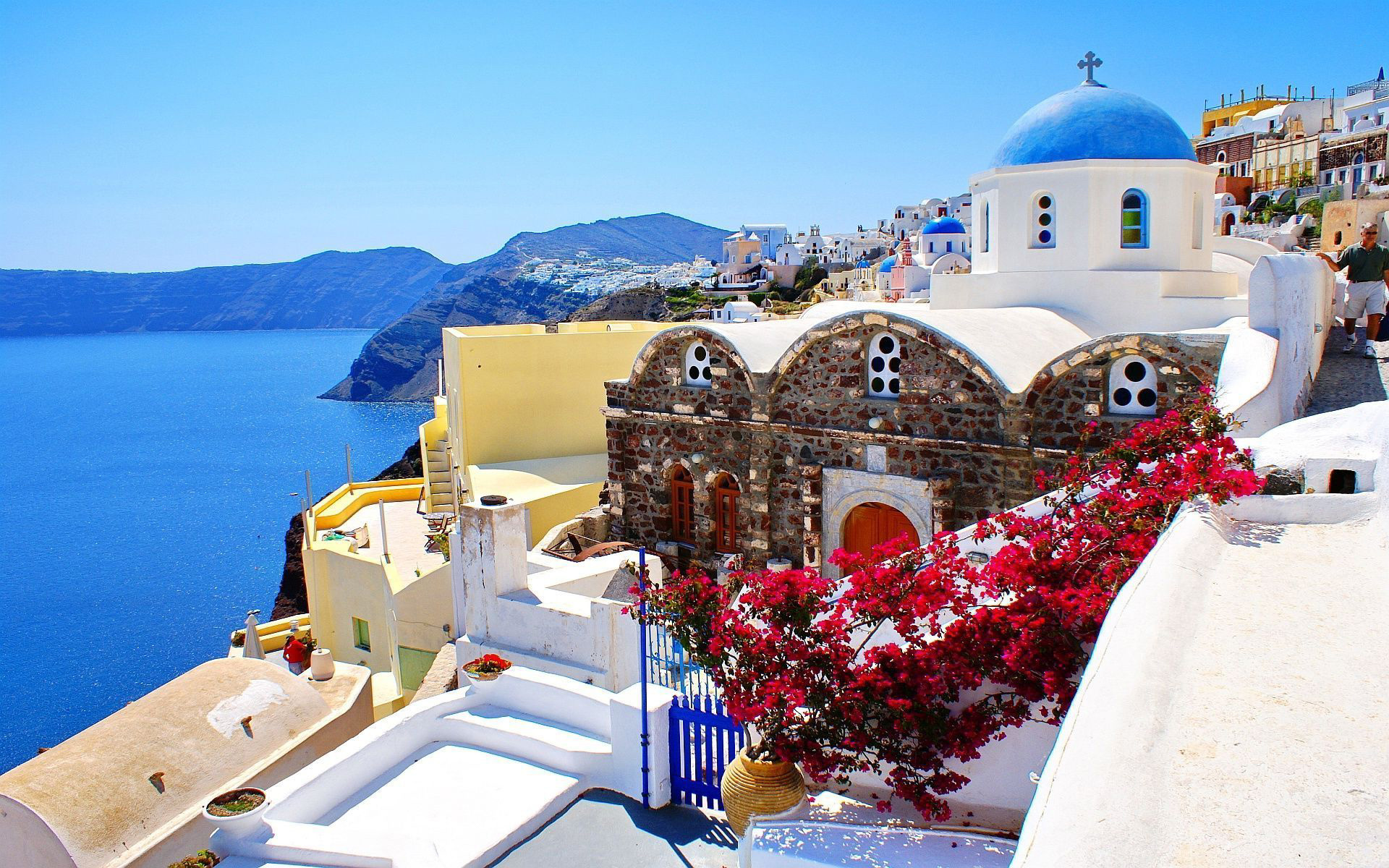 A picturesque whitewashed church with a blue dome overlooks the Aegean Sea in Santorini, Greece