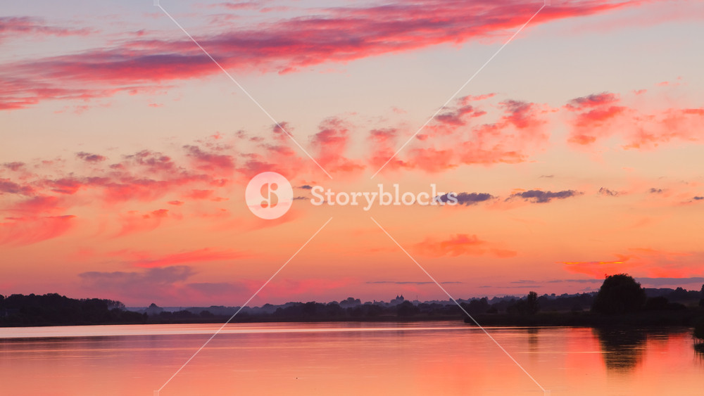 Dramatic Sunset With Red Sky And Clouds Reflections On Still