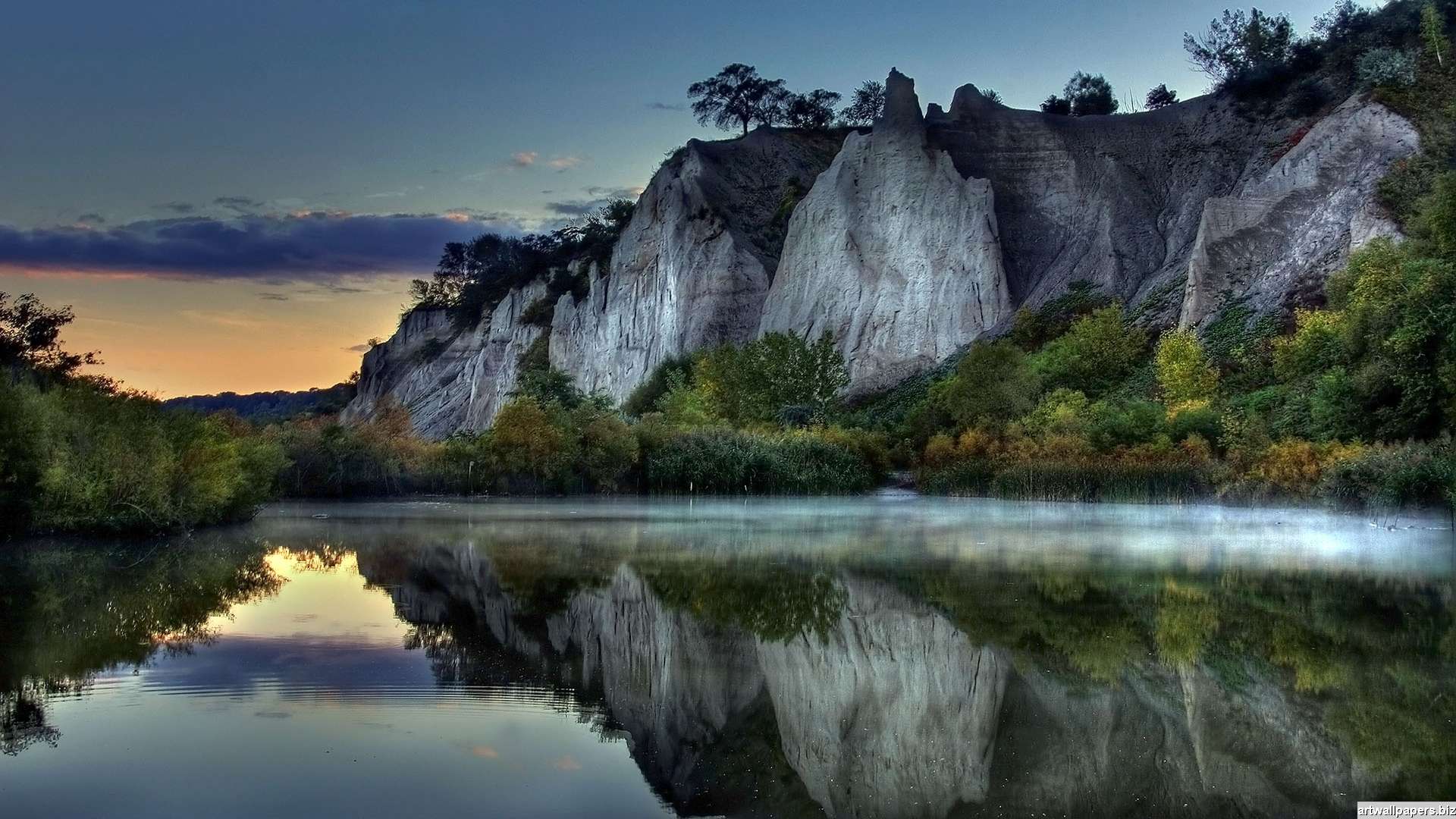 A breathtaking landscape at dawn with towering cliffs reflected in a tranquil lake