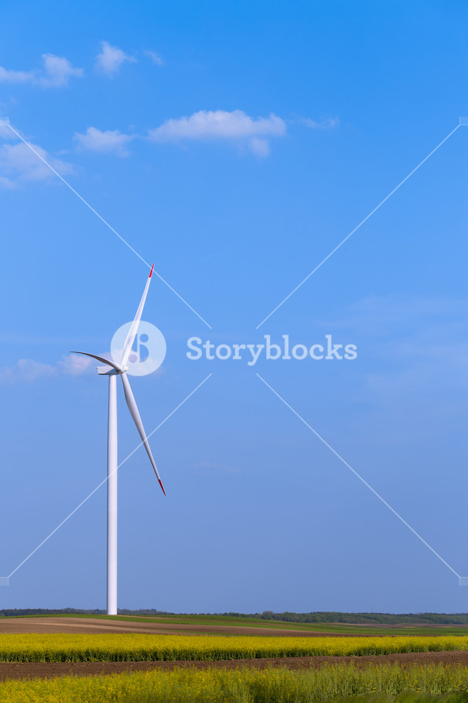 One Single Windmill Turbine On Agricultural Field With Blue Sky In