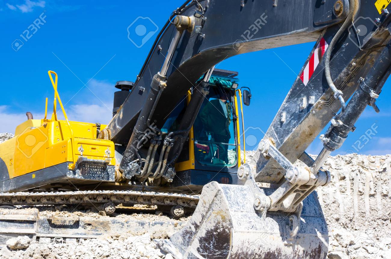The Excavator Digging Clay On Blue Sky Background Stock Photo