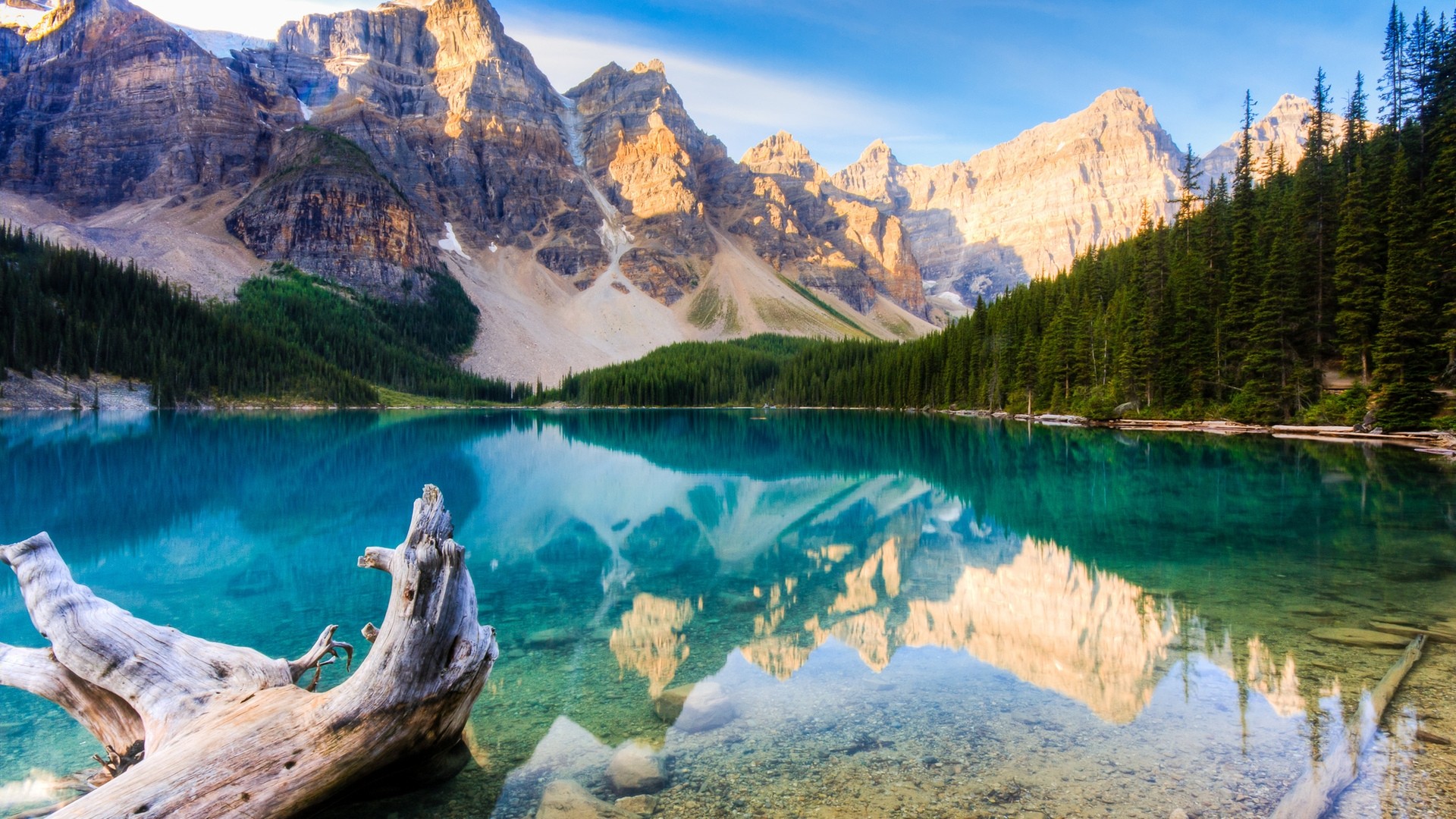 Stunning turquoise lake nestled amidst towering, rugged mountains reflecting in the crystal-clear water with a weathered log in the foreground