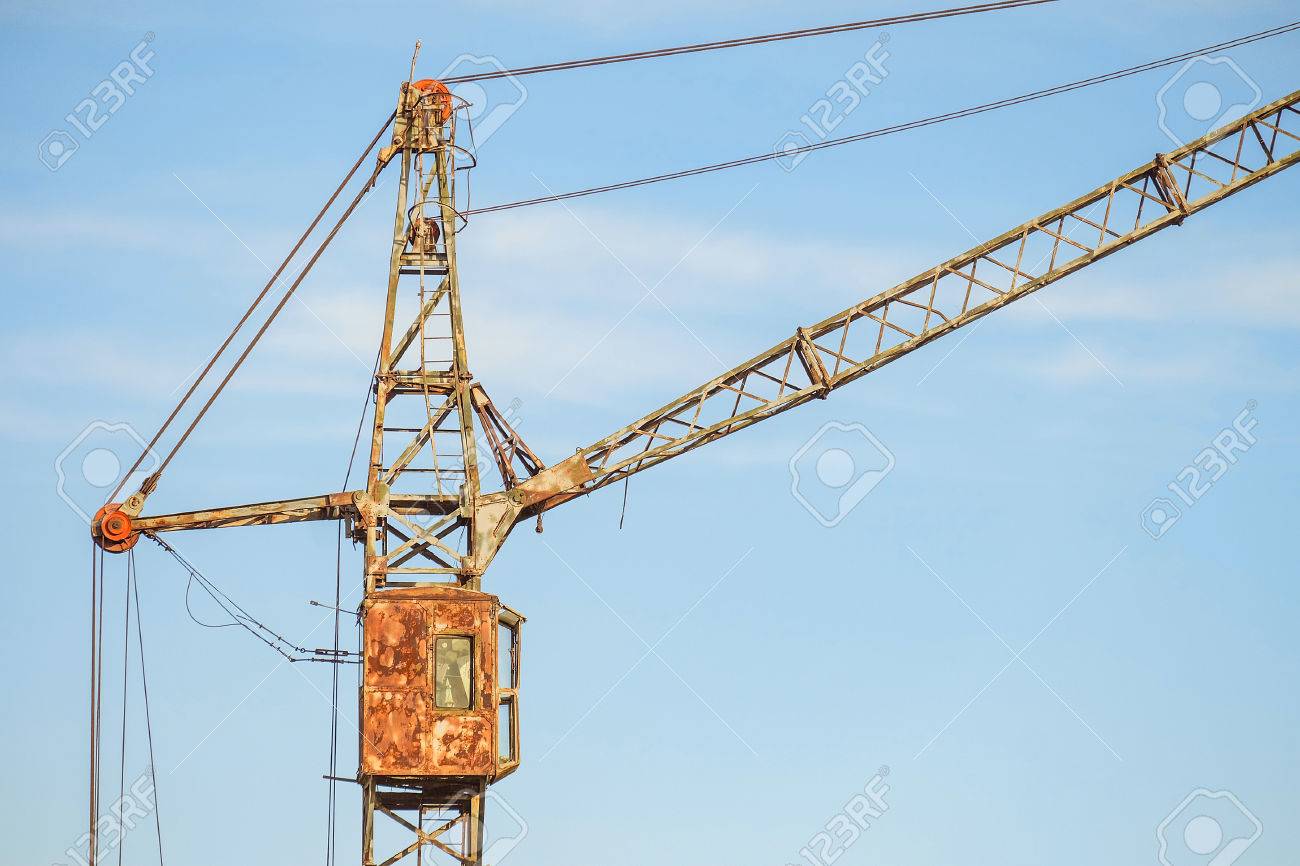 Cabin Of Old Abandoned Rusty Tower Crane On A Blue Sky Background