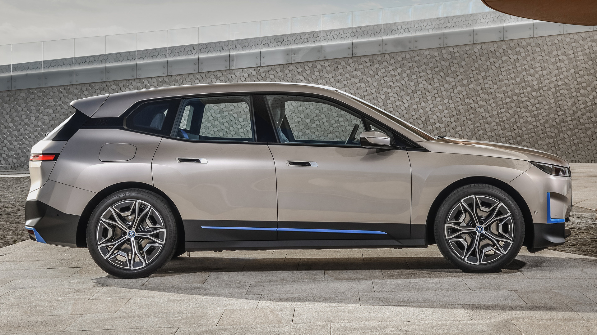 Side view of a BMW iX electric SUV, showcasing its sleek profile, aerodynamic design, and futuristic alloy wheels