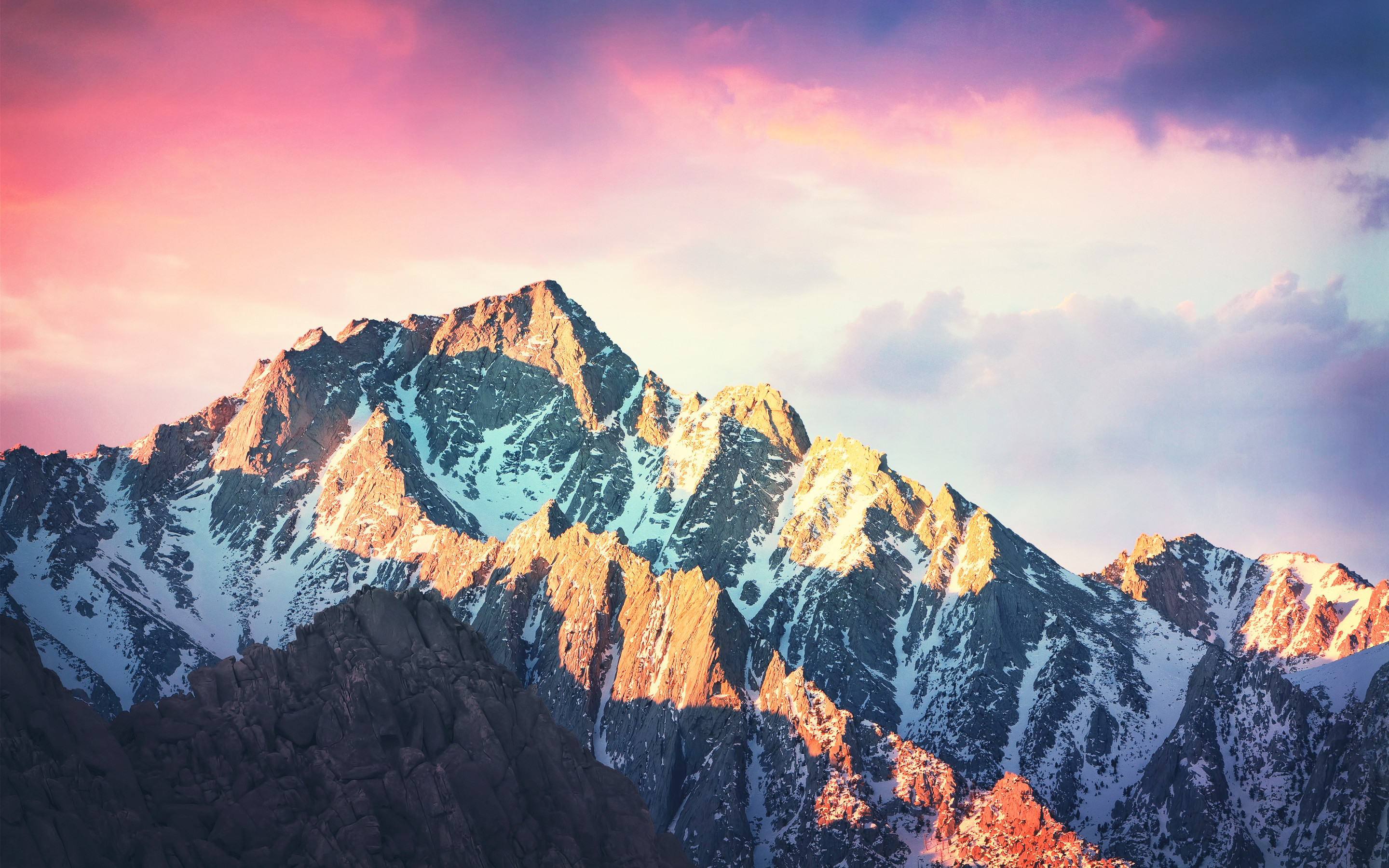 Majestic snow-capped mountain peaks at sunset, perfect for a MacBook wallpaper