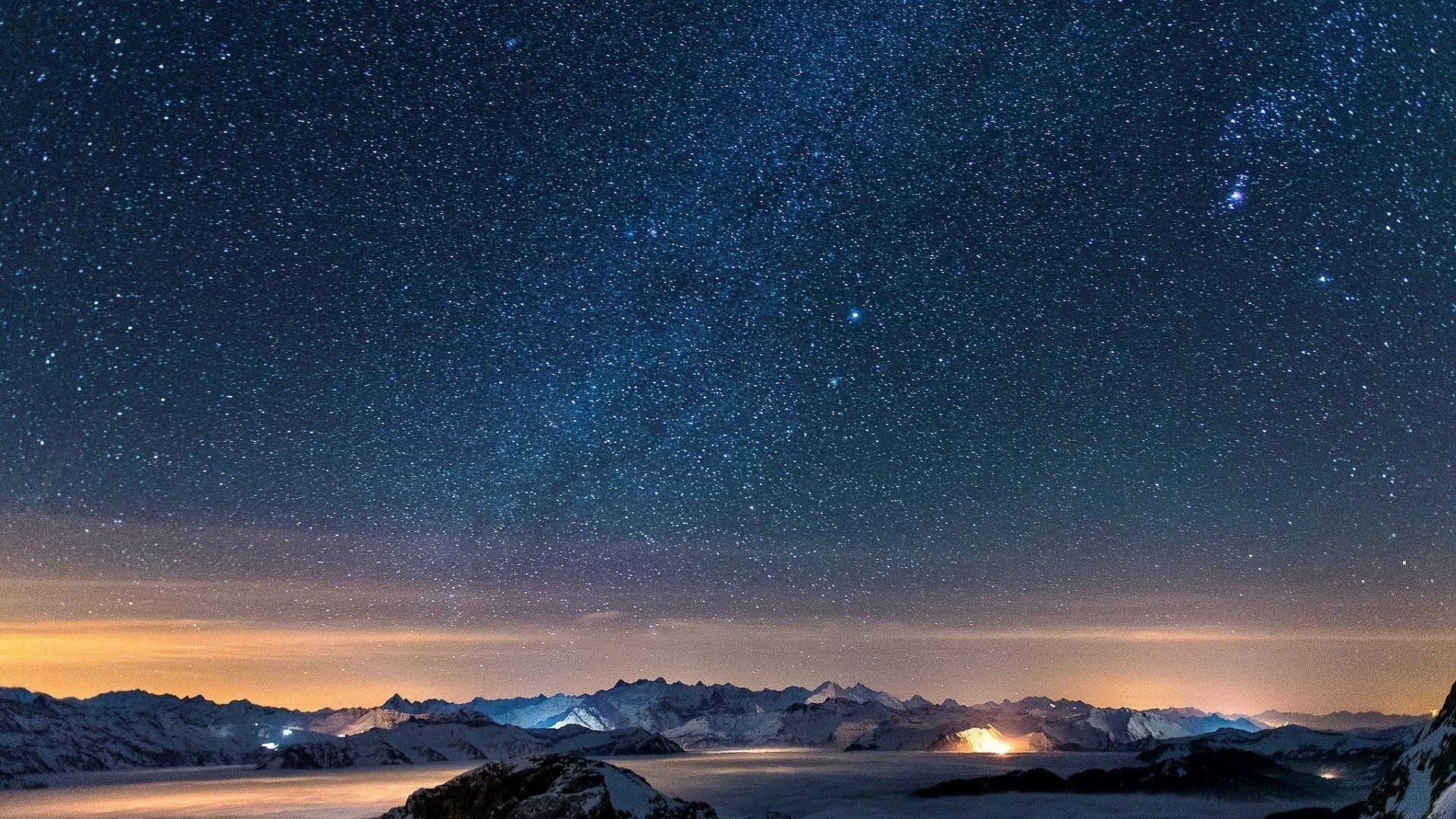 A breathtaking 4K wallpaper of the night sky, showcasing a stunning view of the Milky Way over snow-capped mountains