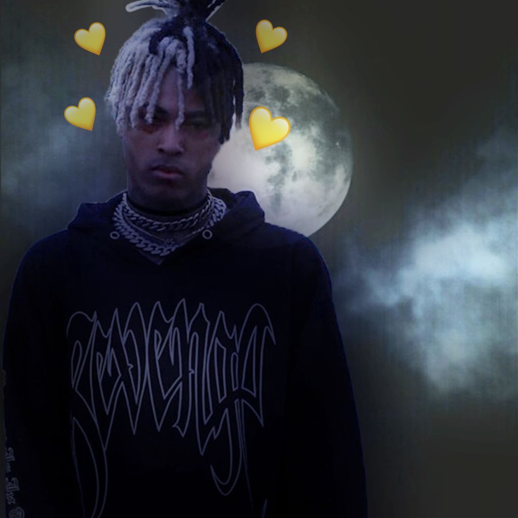 A stylized image of XXXTentacion against a backdrop of a full moon and cloudy night sky. He wears a dark hoodie with a distinctive logo and multiple necklaces. The image has a dark, moody aesthetic with added heart emojis