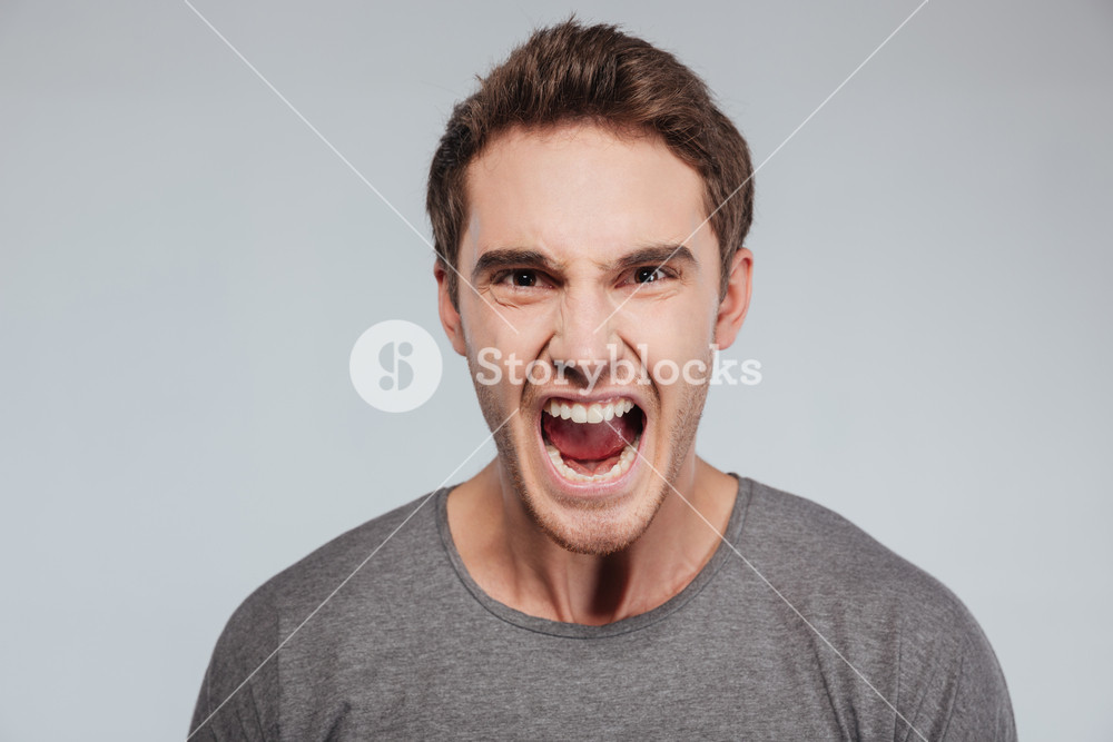 Close Up Portrait Of A Young Casual Man Screaming At Camera Over