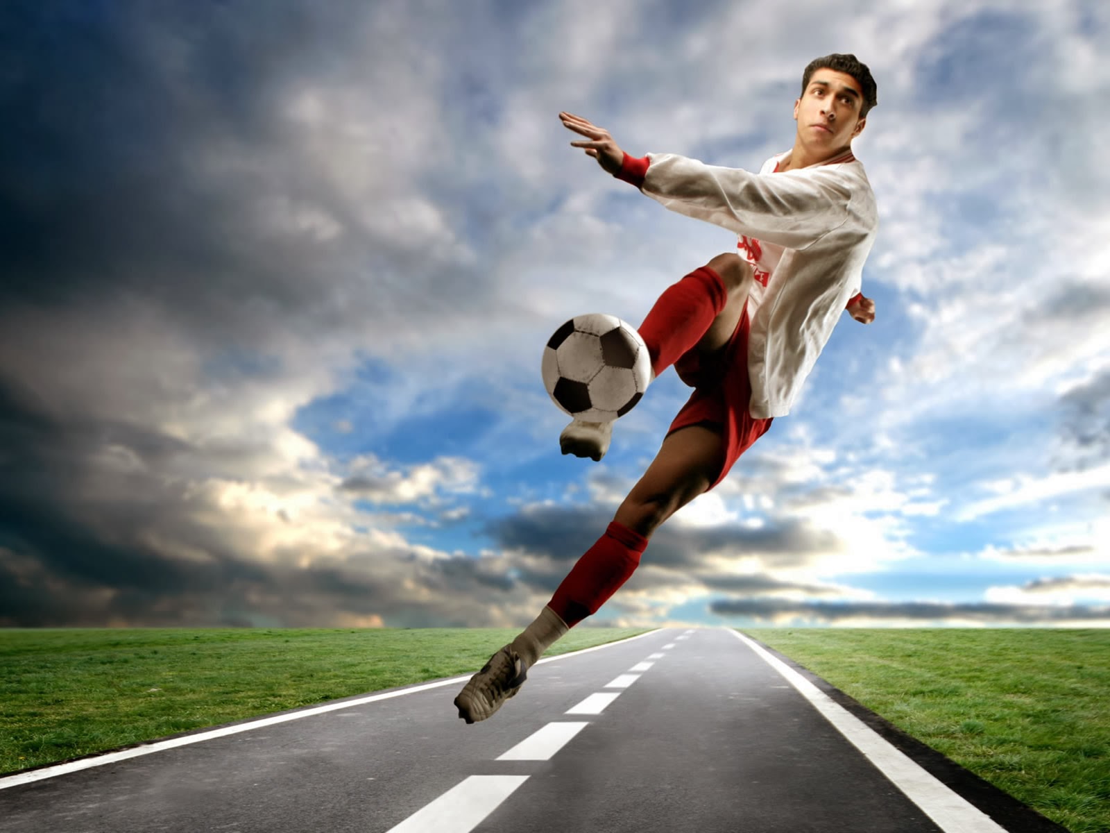 A soccer player dynamically kicks the ball mid-air on a paved road against a dramatic sky backdrop
