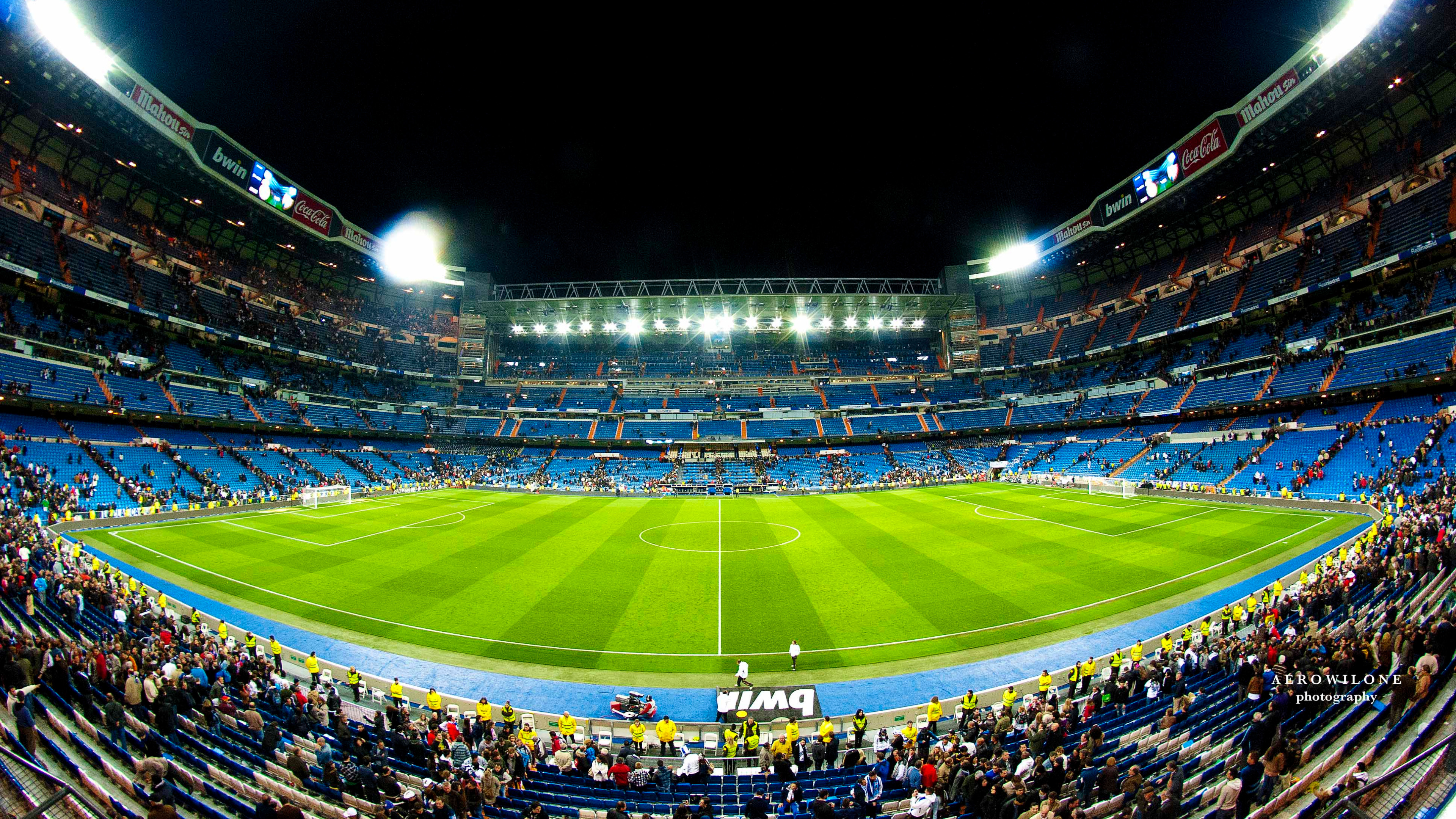A panoramic view of the Santiago Bernabéu Stadium, home of Real Madrid, illuminated at night and filled with fans