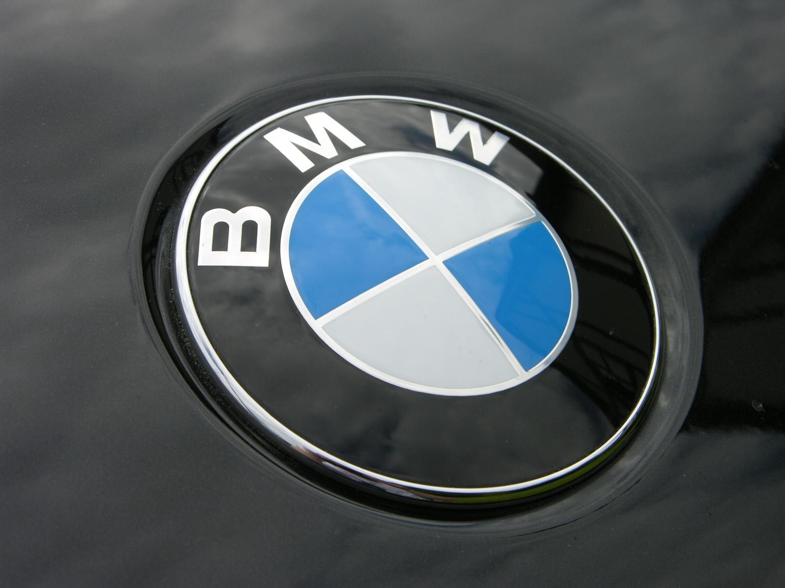 Close-up of a BMW logo on a black car hood, showcasing the iconic blue and white roundel