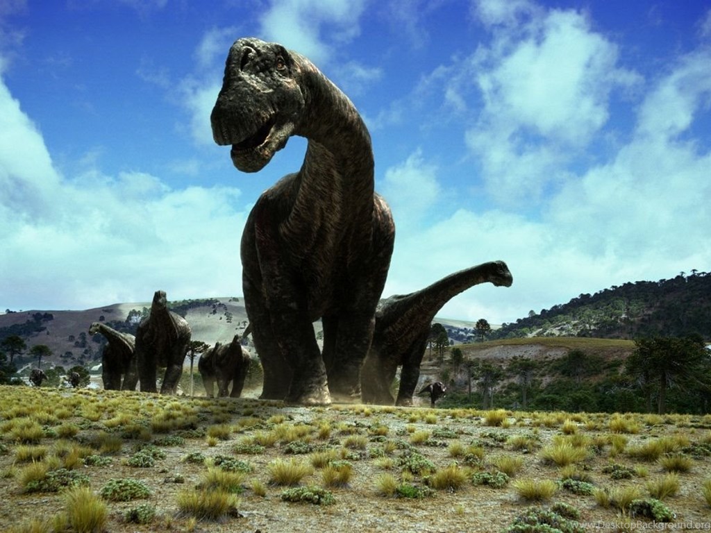 A herd of large, long-necked dinosaurs traverses a grassy plain under a blue sky. This image evokes a prehistoric scene, possibly from the Mesozoic Era
