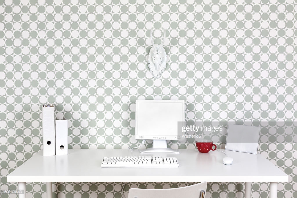 Desk At Home Office With White Accessories In Front Of Patterned